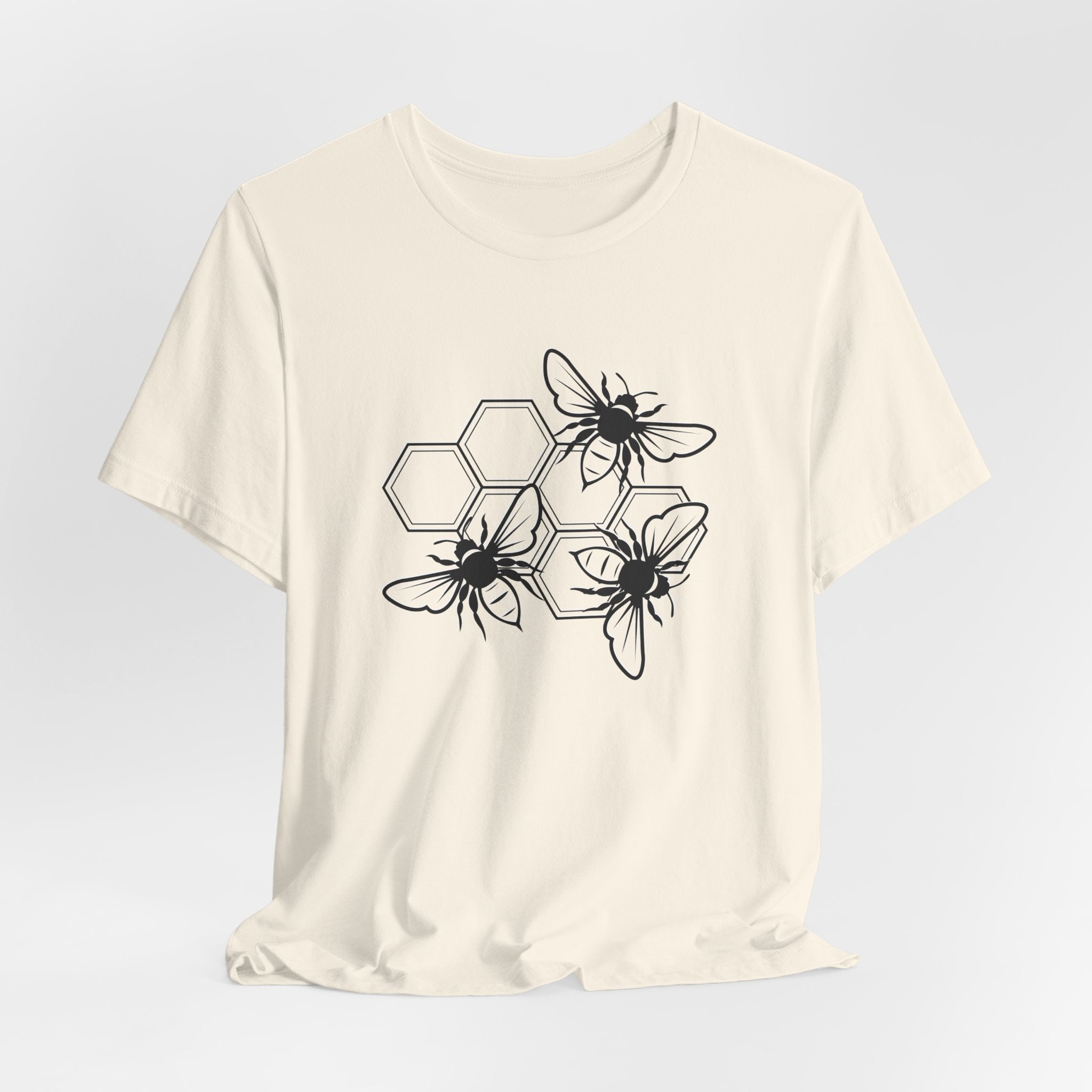 White t-shirt with black bee and hexagon pattern on a light gray background