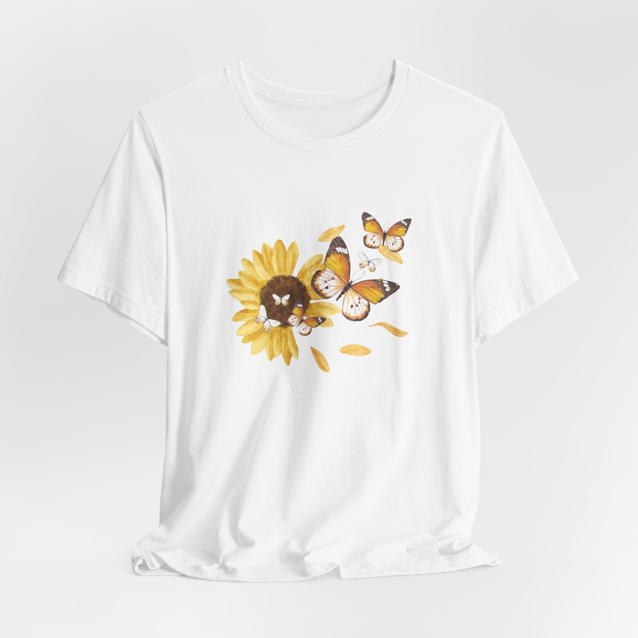 White t-shirt with a sunflower and butterfly graphic on a light gray background