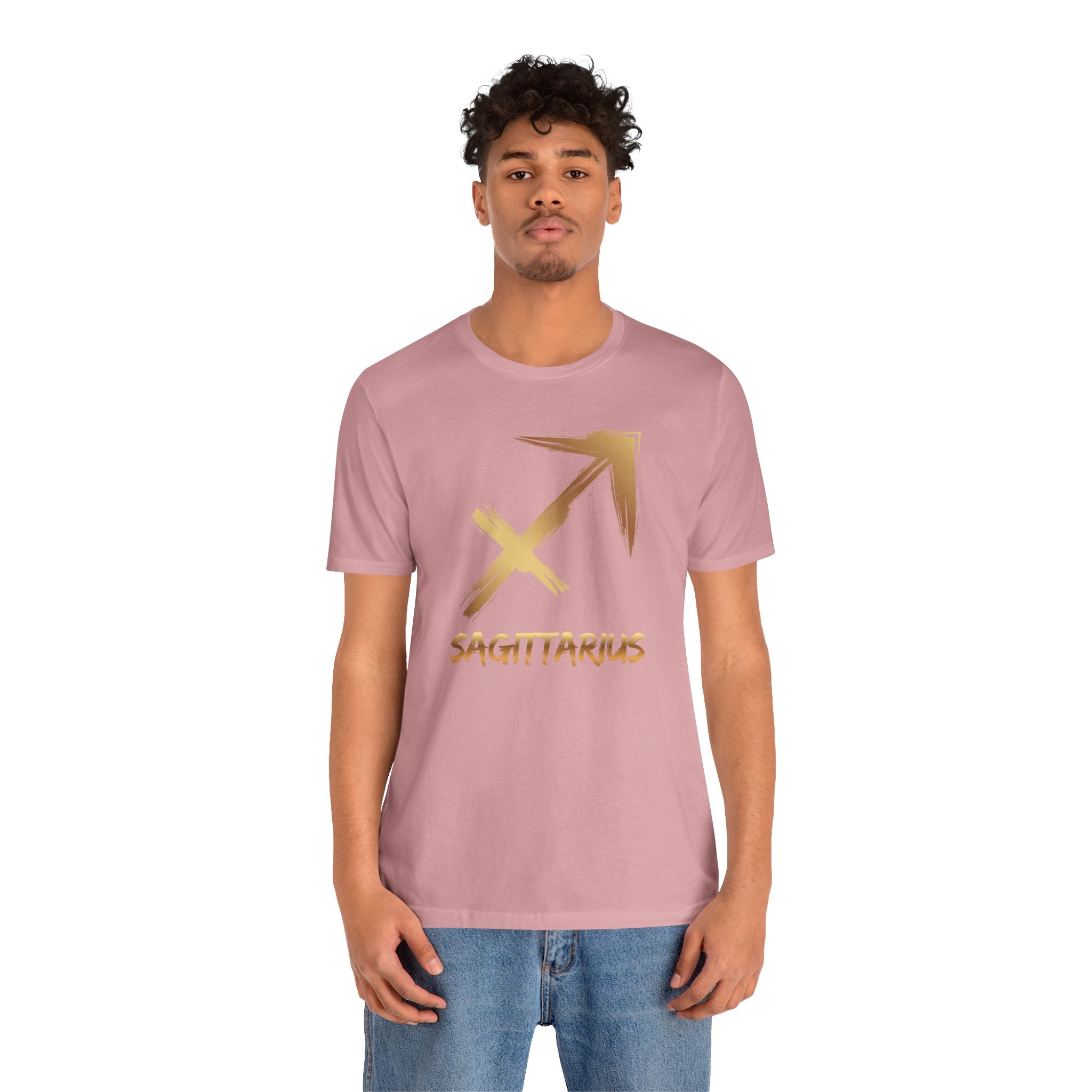 Person wearing a pink t-shirt with a gold Sagittarius symbol on a white background