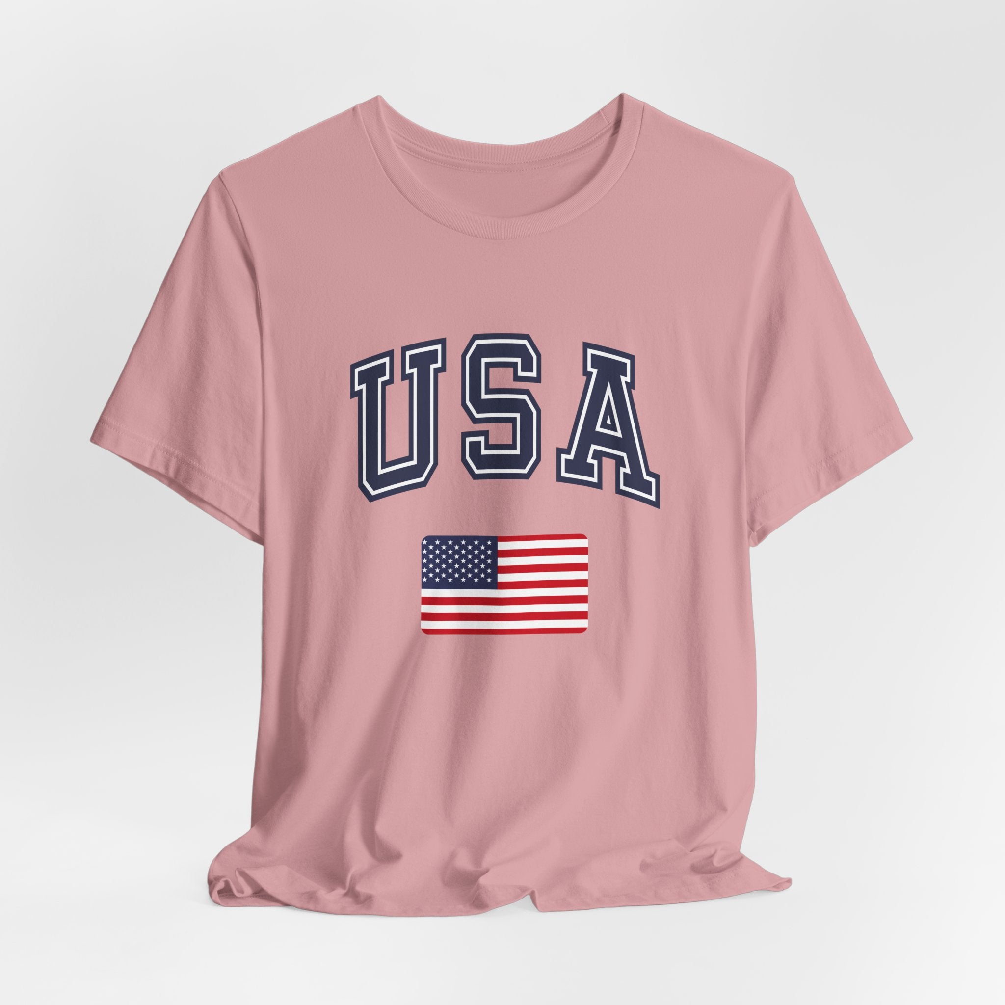 Pink t-shirt with 'USA' text and American flag on a light gray background