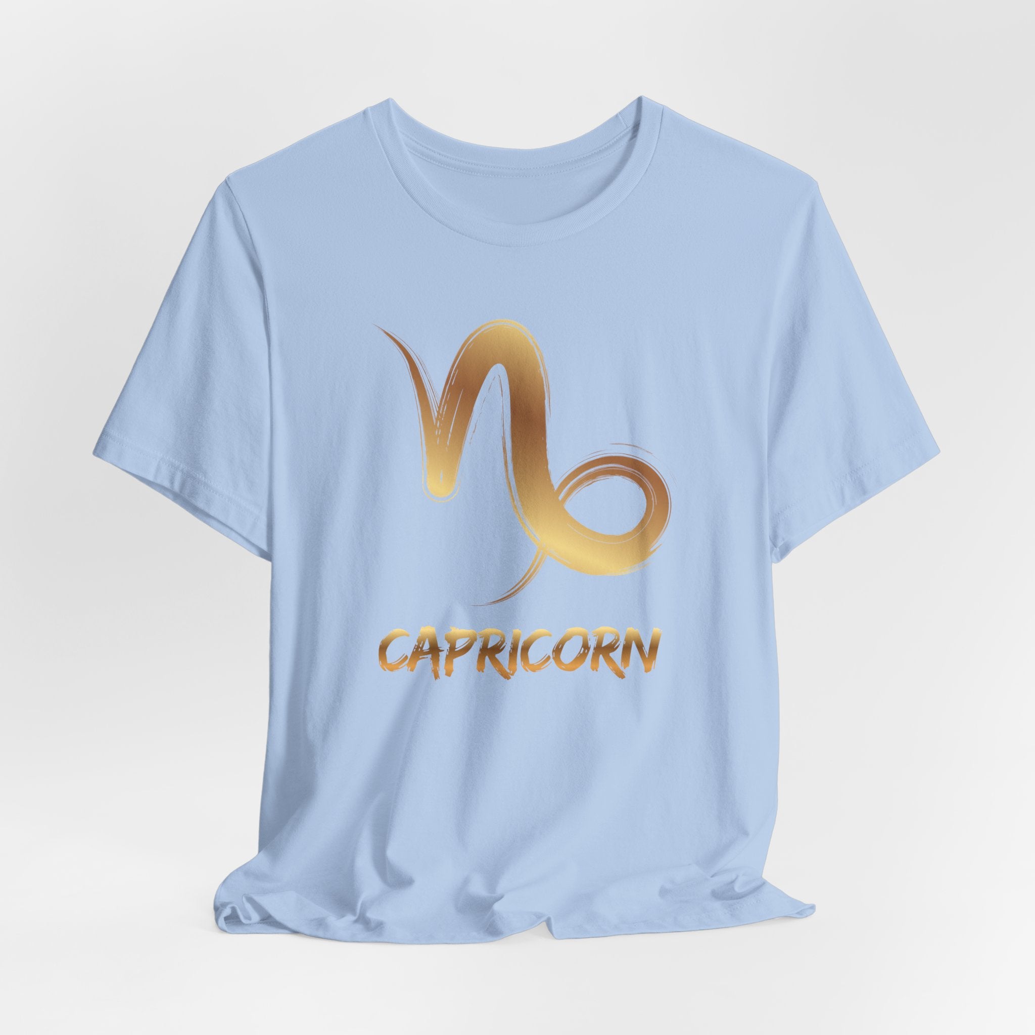 Light blue t-shirt with gold Capricorn zodiac symbol on a light gray background