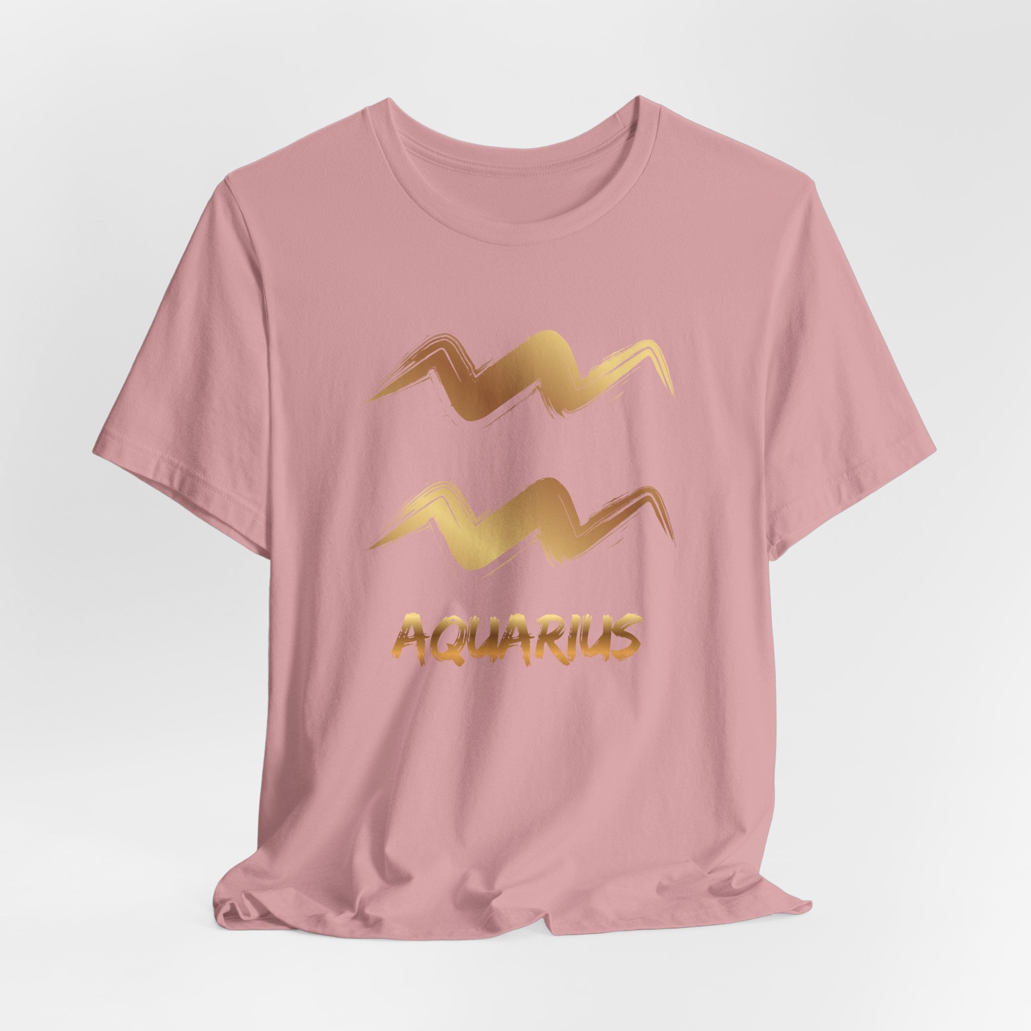 Pink t-shirt with gold Aquarius zodiac symbol on a light gray background