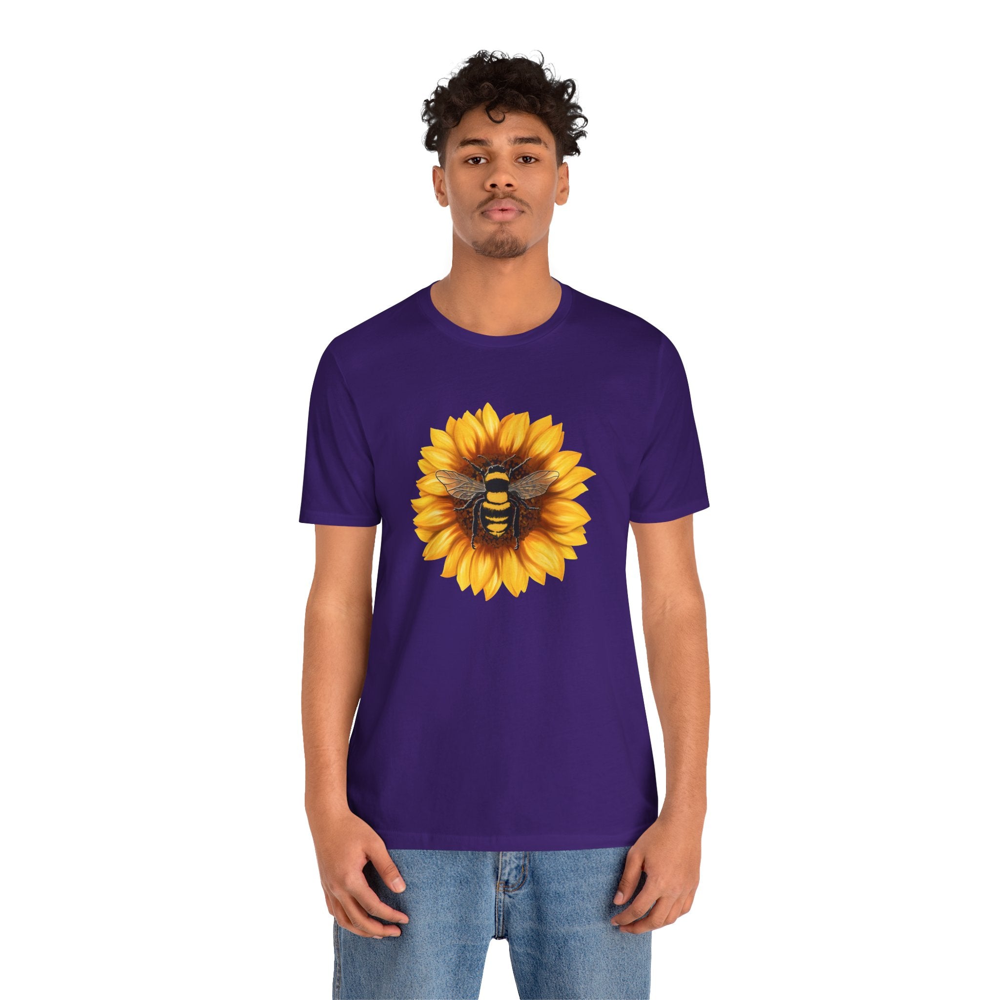 Person wearing a purple t-shirt with a sunflower and bee design on a white background