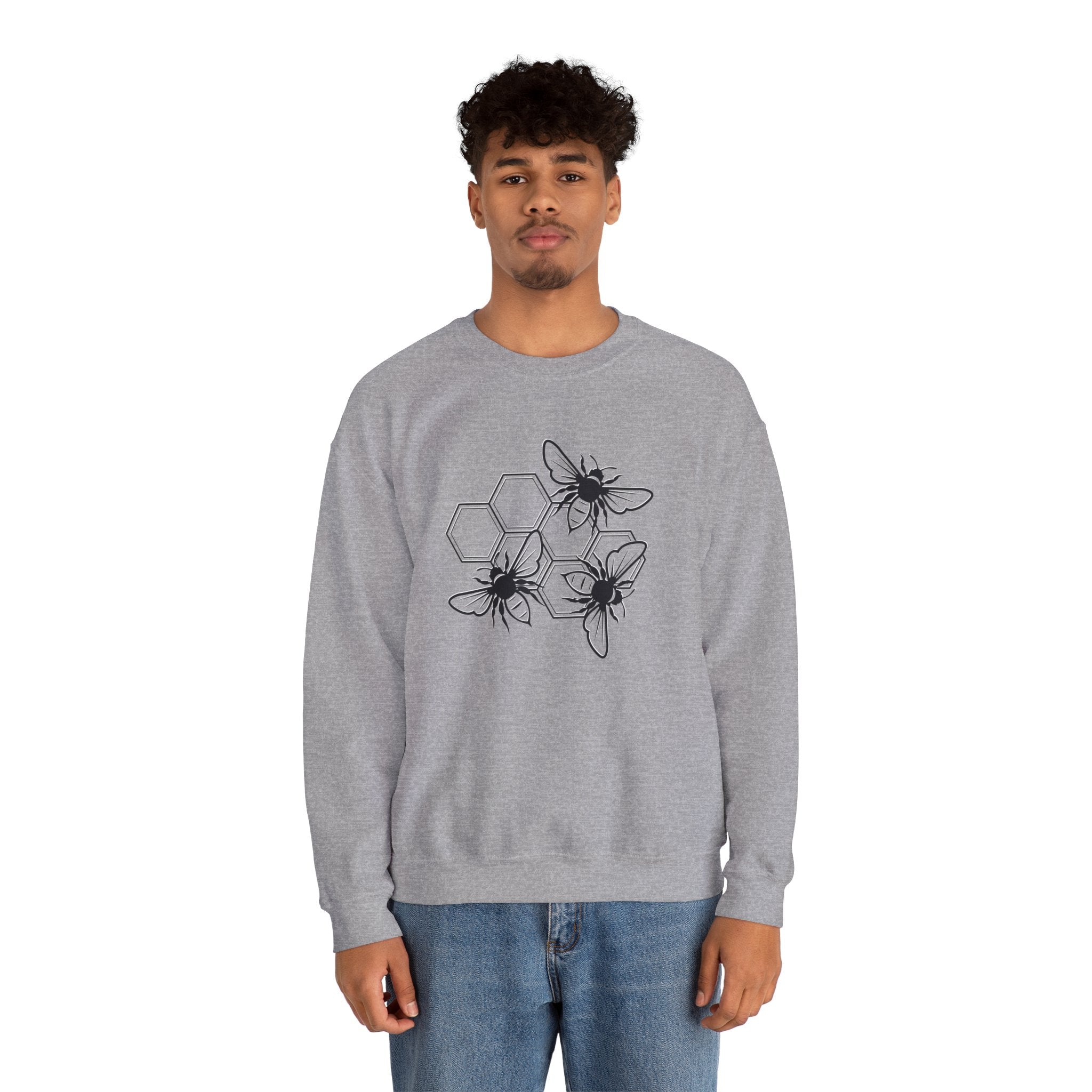 Person wearing a gray sweatshirt with black bee and hexagon pattern on a white background