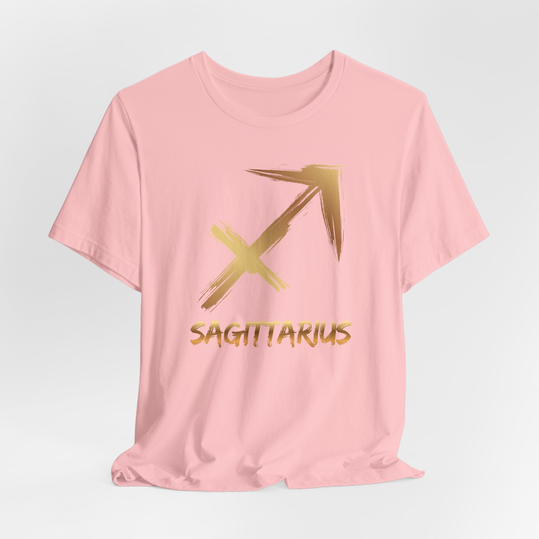 Pink t-shirt with gold Sagittarius symbol and text on a light gray background