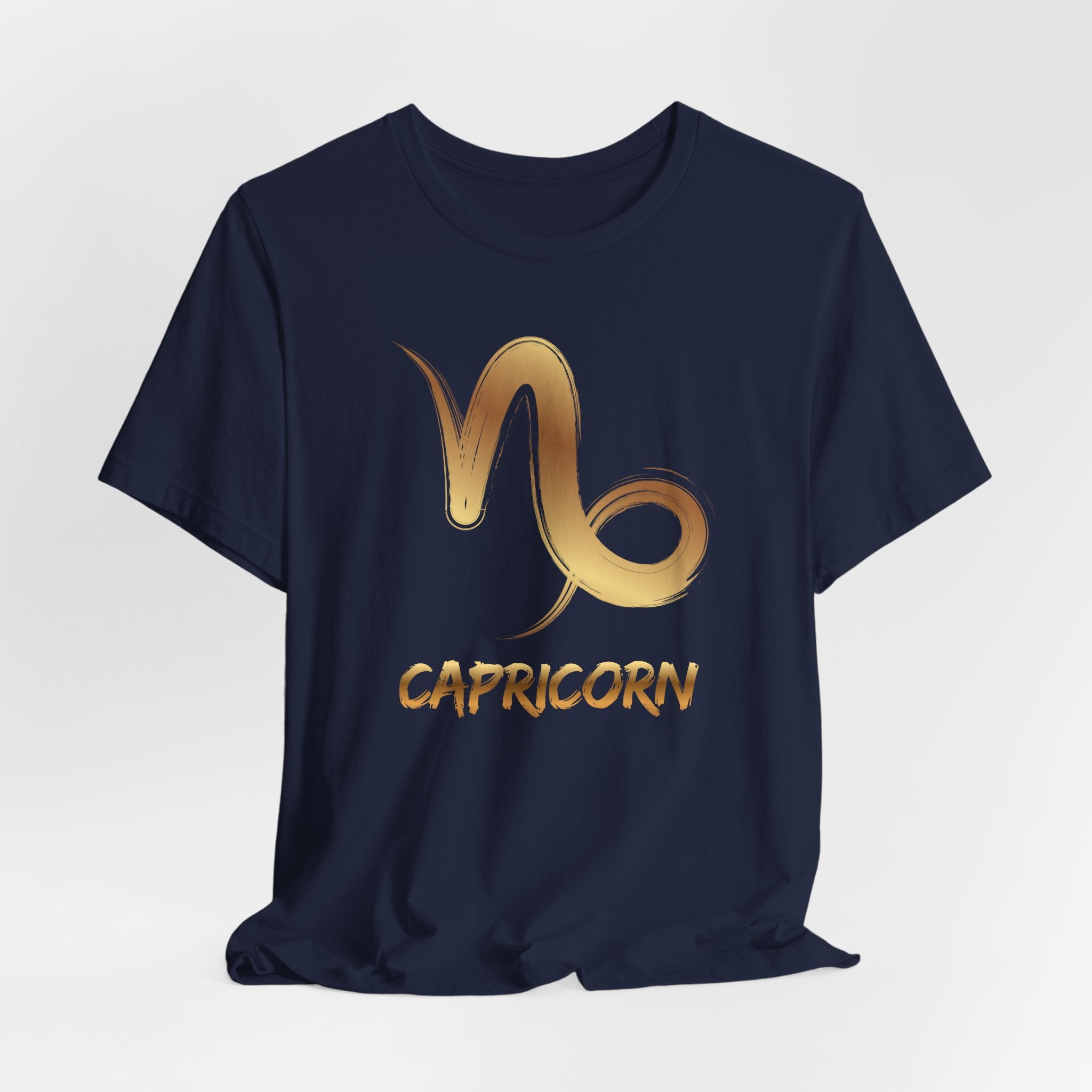 Navy blue t-shirt with gold Capricorn zodiac symbol on a light gray background