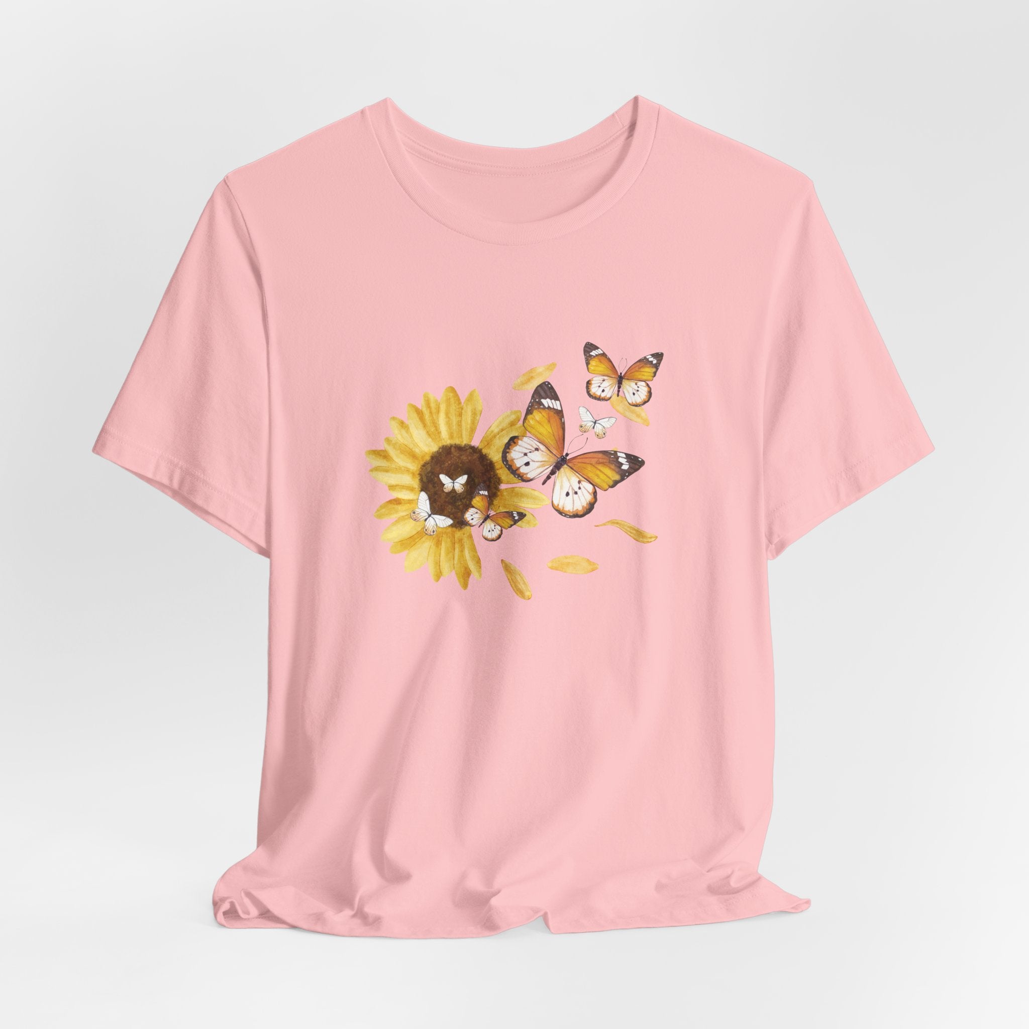 Pink t-shirt with butterfly and sunflower design on a light gray background