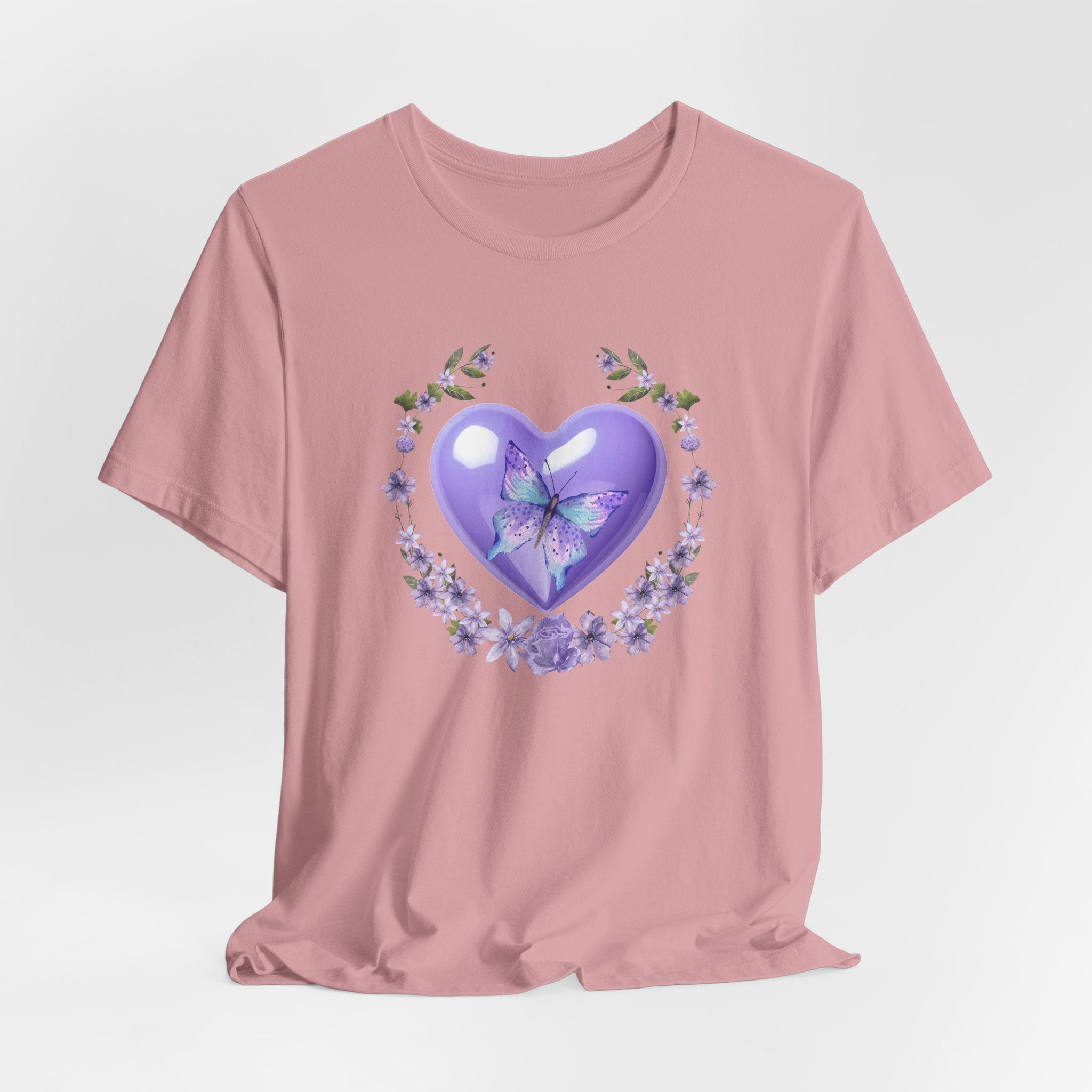 Pink t-shirt with a purple heart and butterfly design on a light gray background