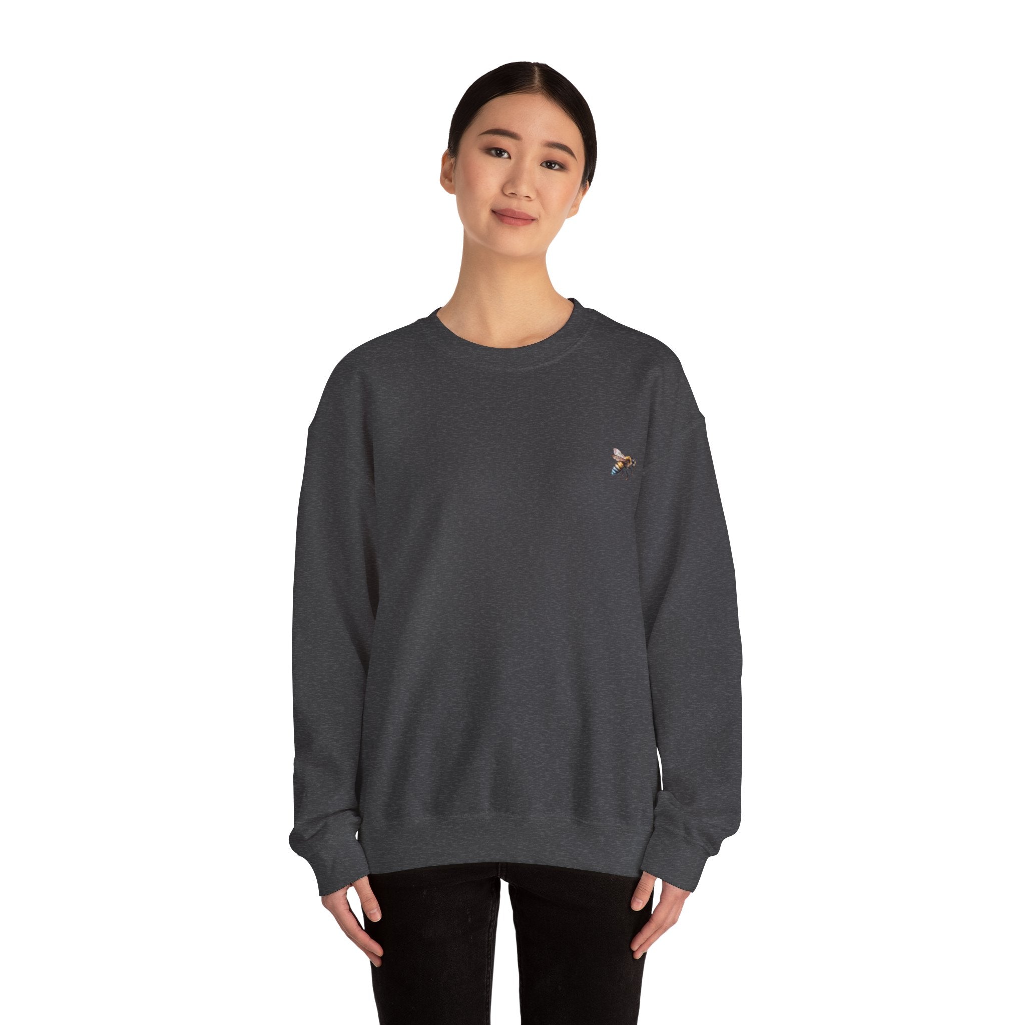 Person wearing a dark gray sweatshirt with a small bee logo on a white background