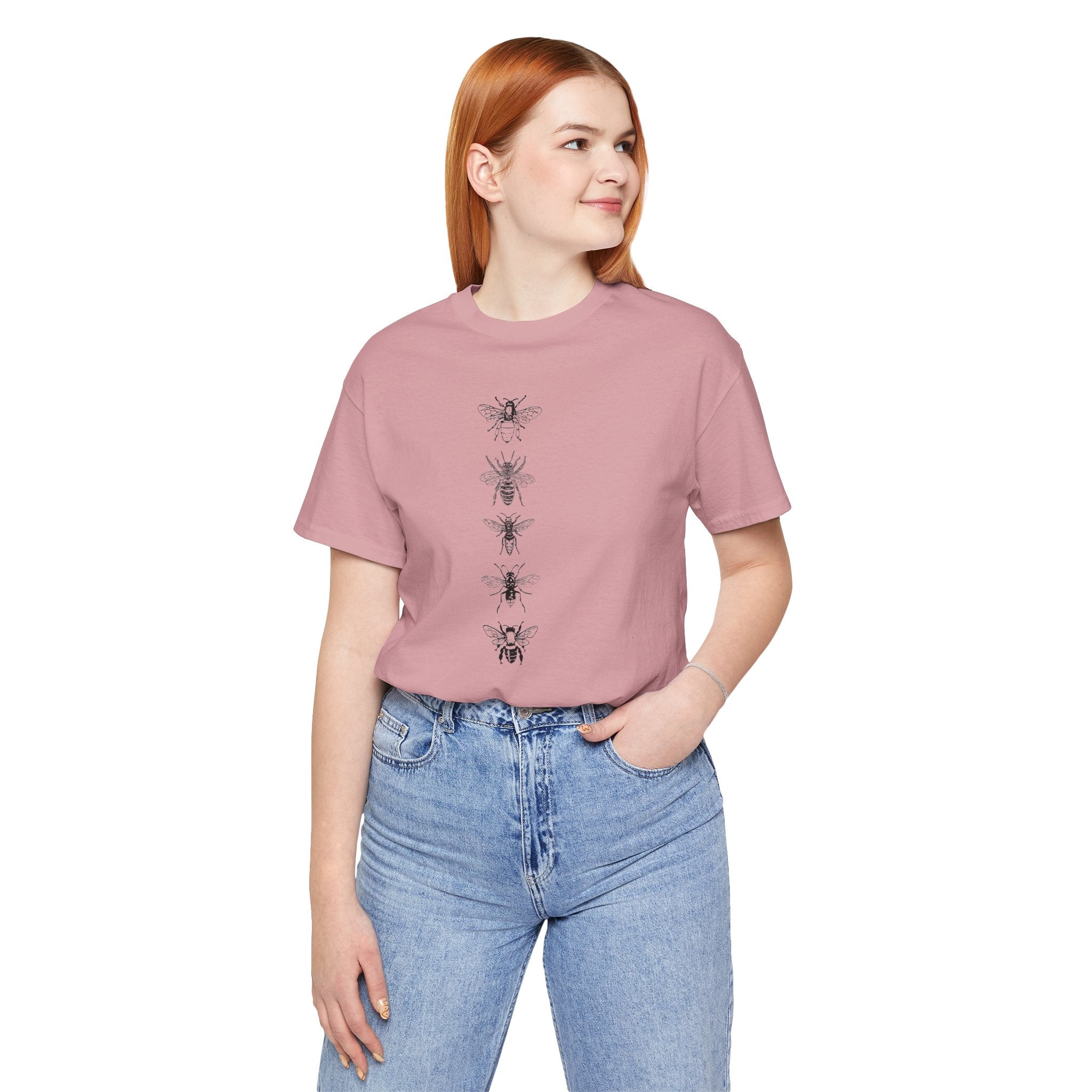 Person wearing a pink t-shirt with graphic design and blue jeans on a white background