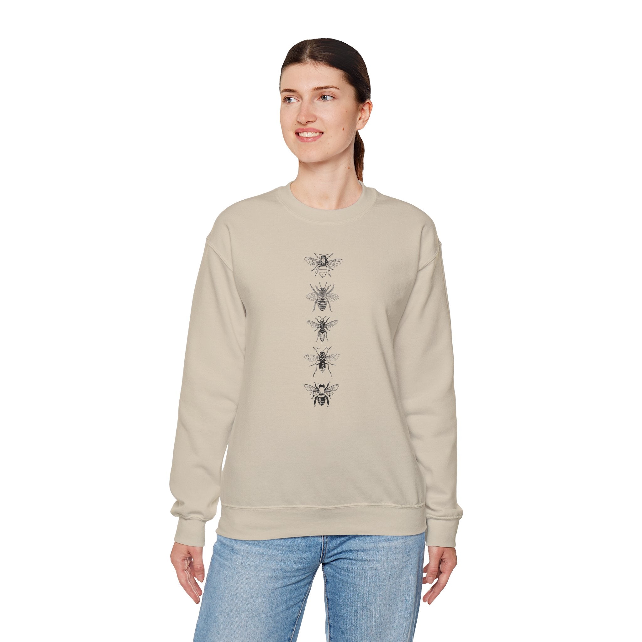 Woman wearing a beige sweatshirt with black bee illustrations on a white background