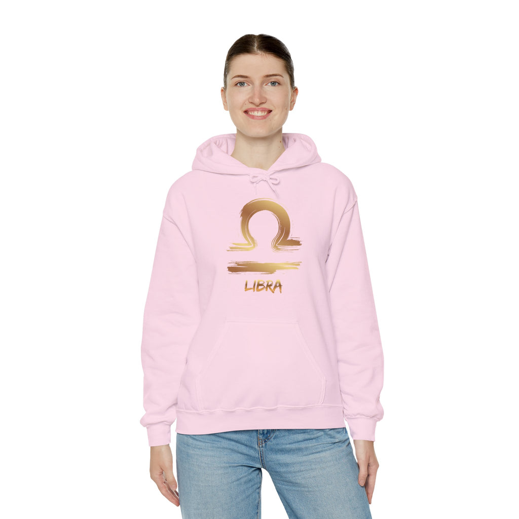 Person wearing a pink hoodie with a gold Libra zodiac symbol on a white background
