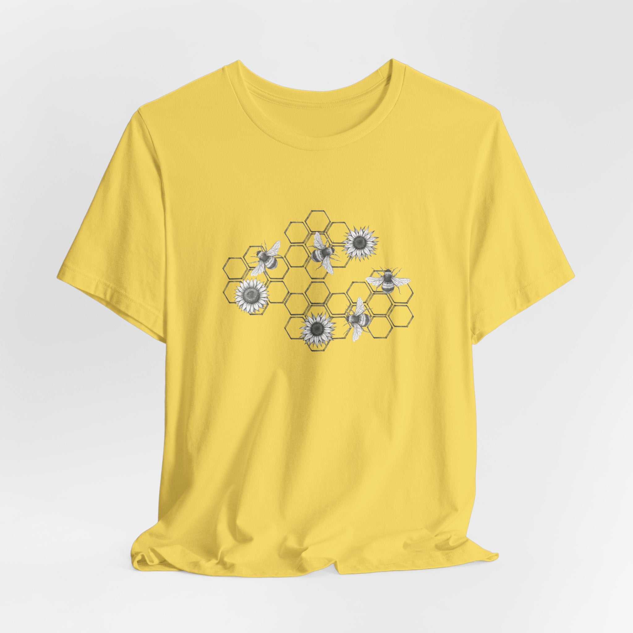 Yellow t-shirt with a honeycomb and flower design on a light gray background