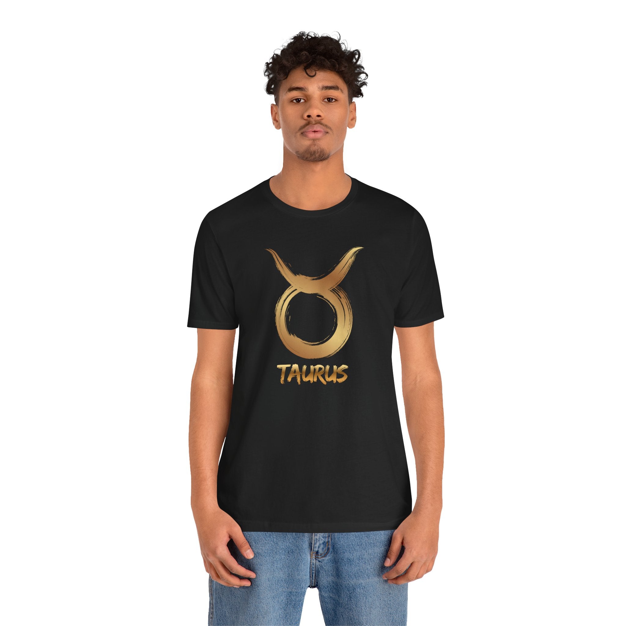Person wearing a black t-shirt with a gold Taurus symbol design on a white background