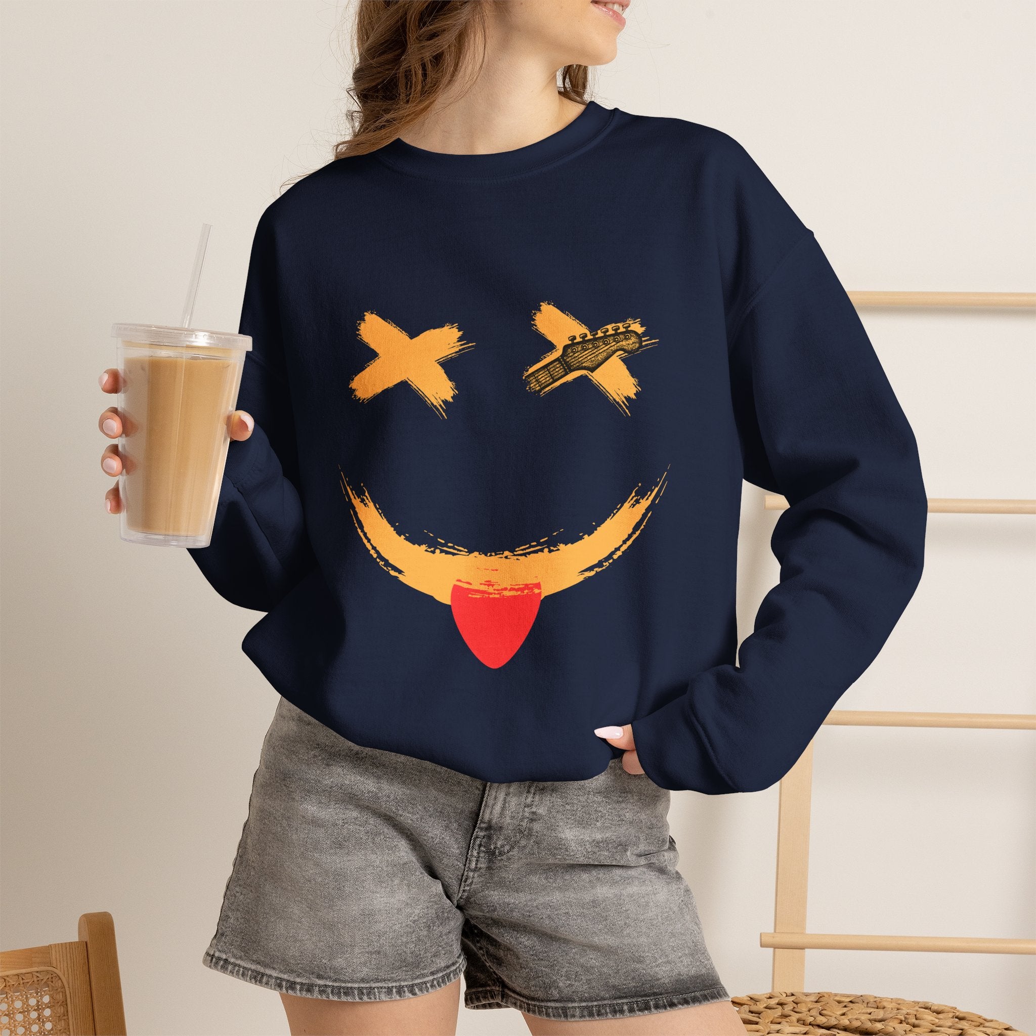 Person wearing a navy blue sweatshirt with a smiley guitar face design on a white background