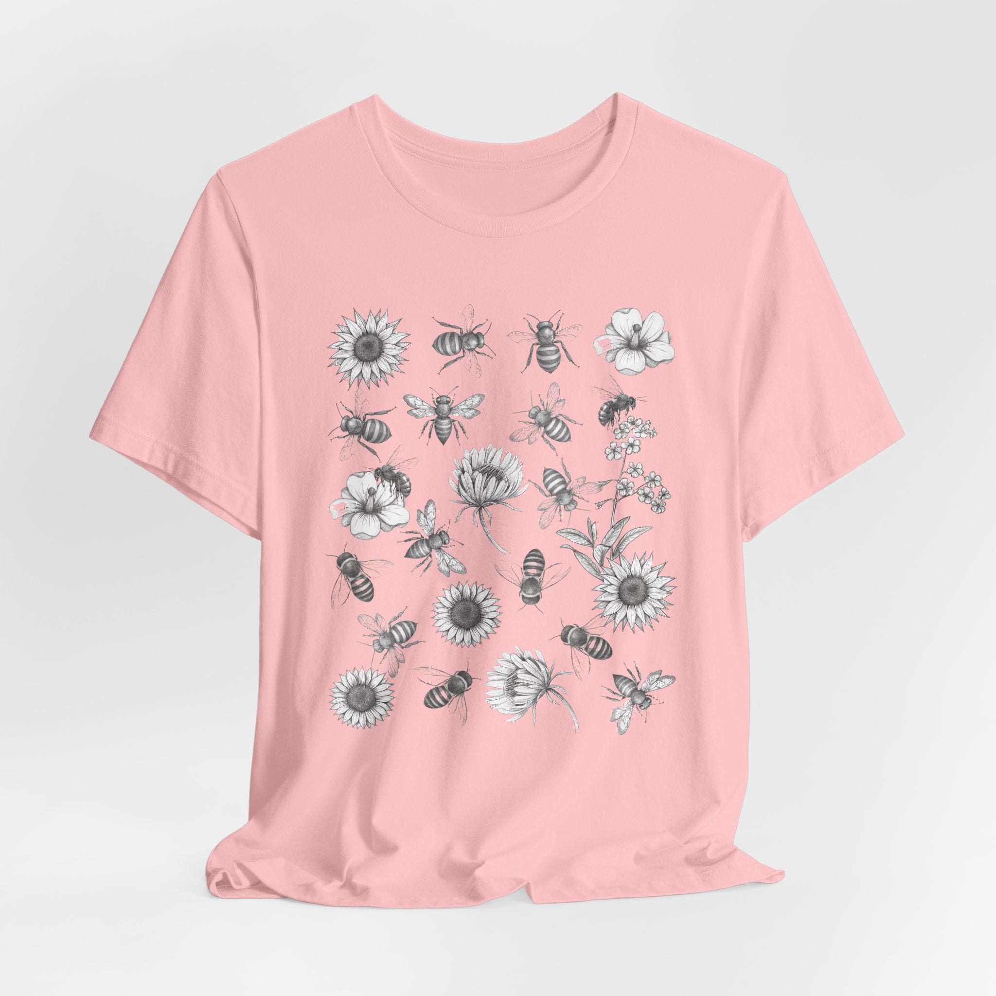 Pink t-shirt with floral and bee design on a light gray background
