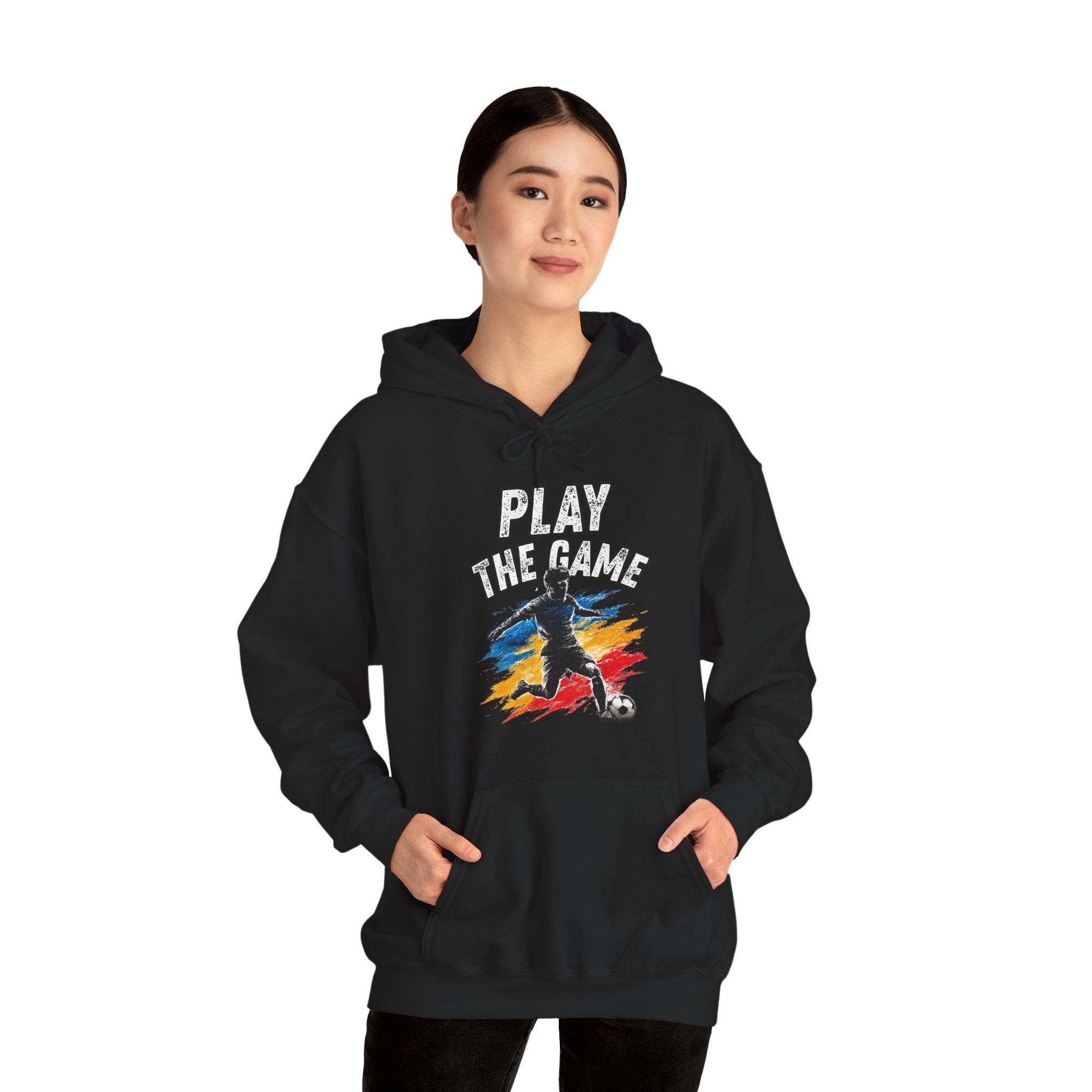 Person wearing a black hoodie featuring a graphic print on the front with the text 'PLAY THE GAME' above a stylized soccer player silhouette over a red, yellow, and blue paint-splatter background.