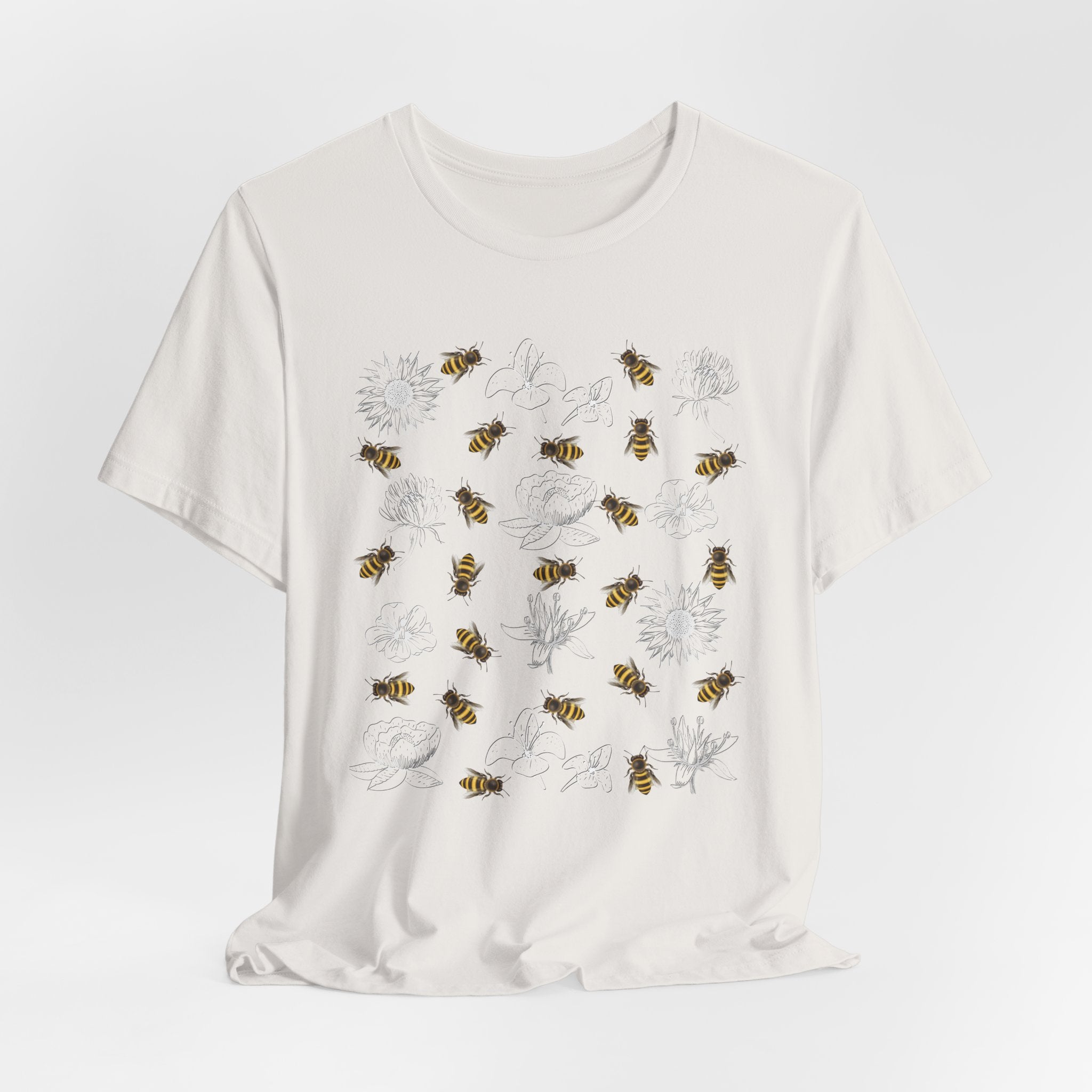 White t-shirt with bee and flower pattern on a light gray background