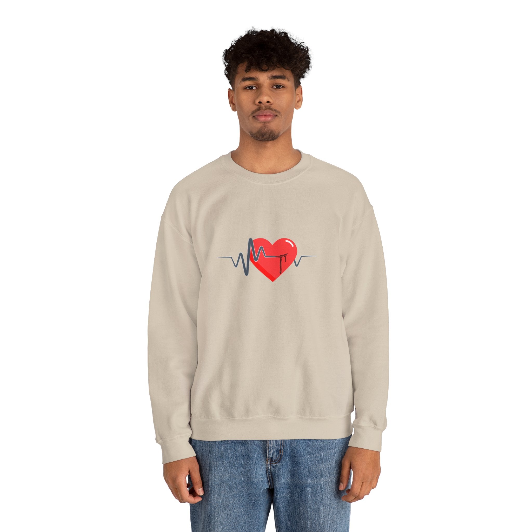 Person wearing a beige sweatshirt with a red heart and black design on a white background