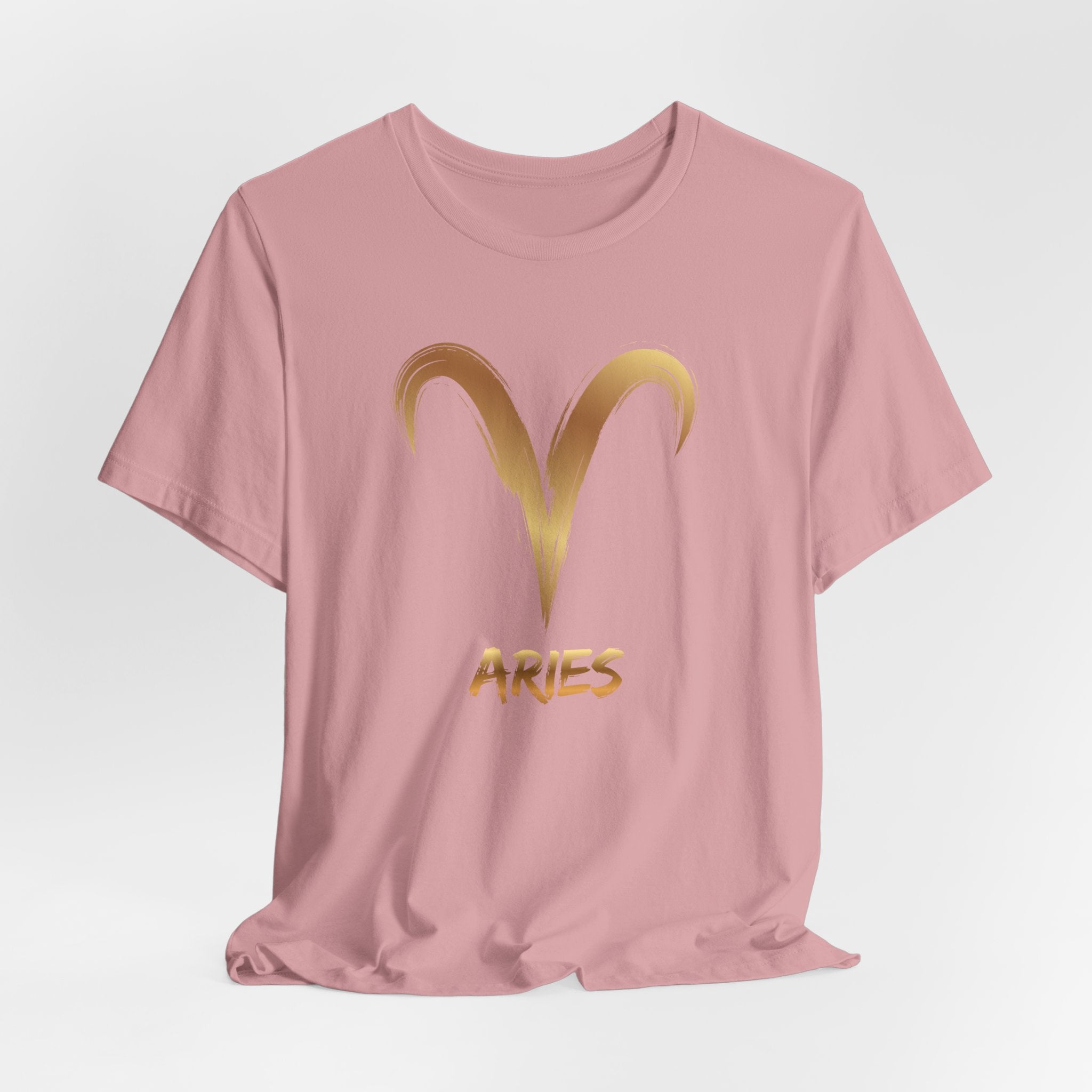 Pink t-shirt with gold Aries symbol on a light gray background