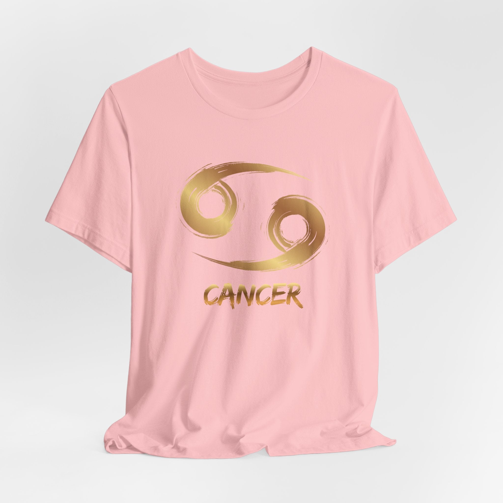 Pink t-shirt with gold Cancer zodiac symbol on a light gray background