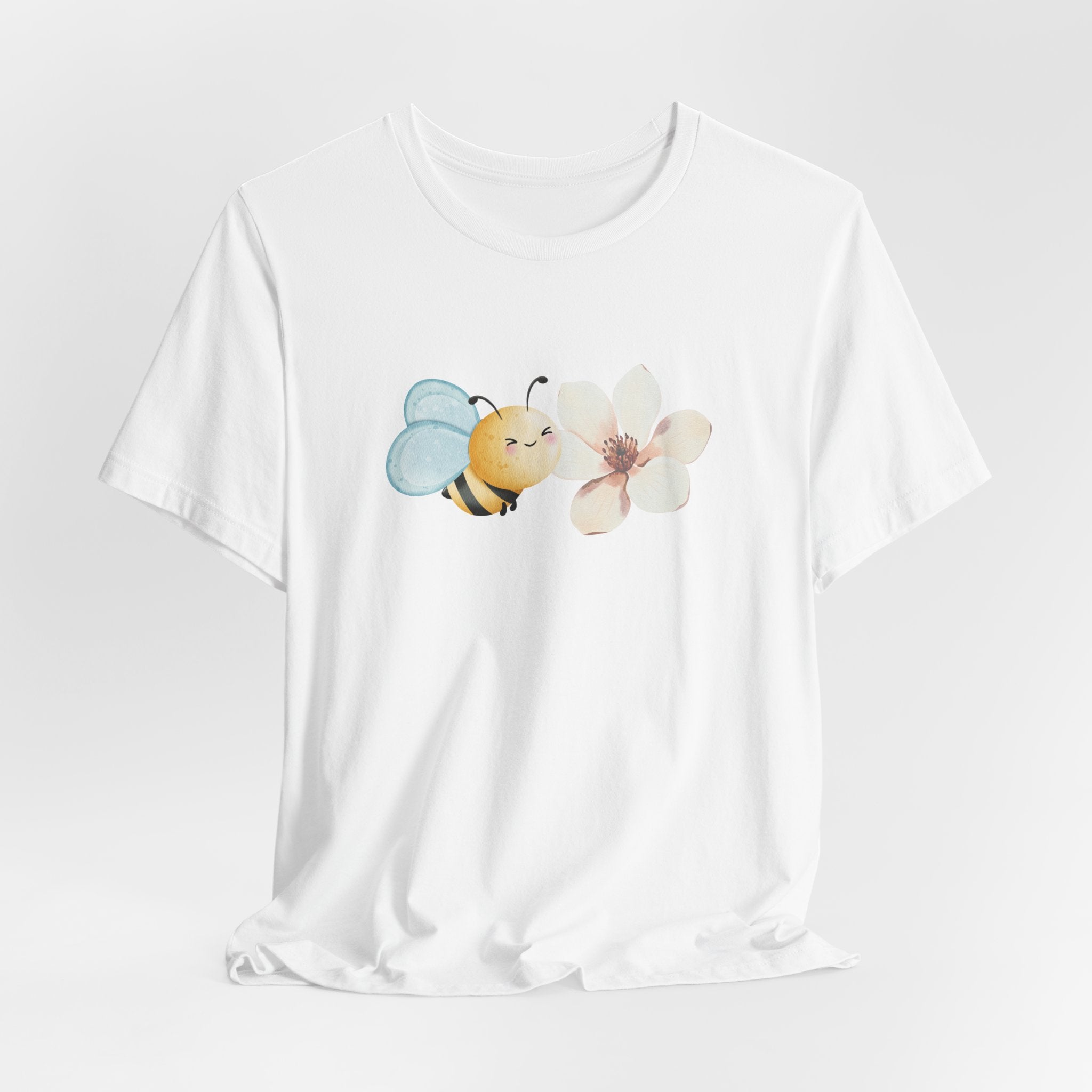 White t-shirt with a bee and flower design on a light gray background