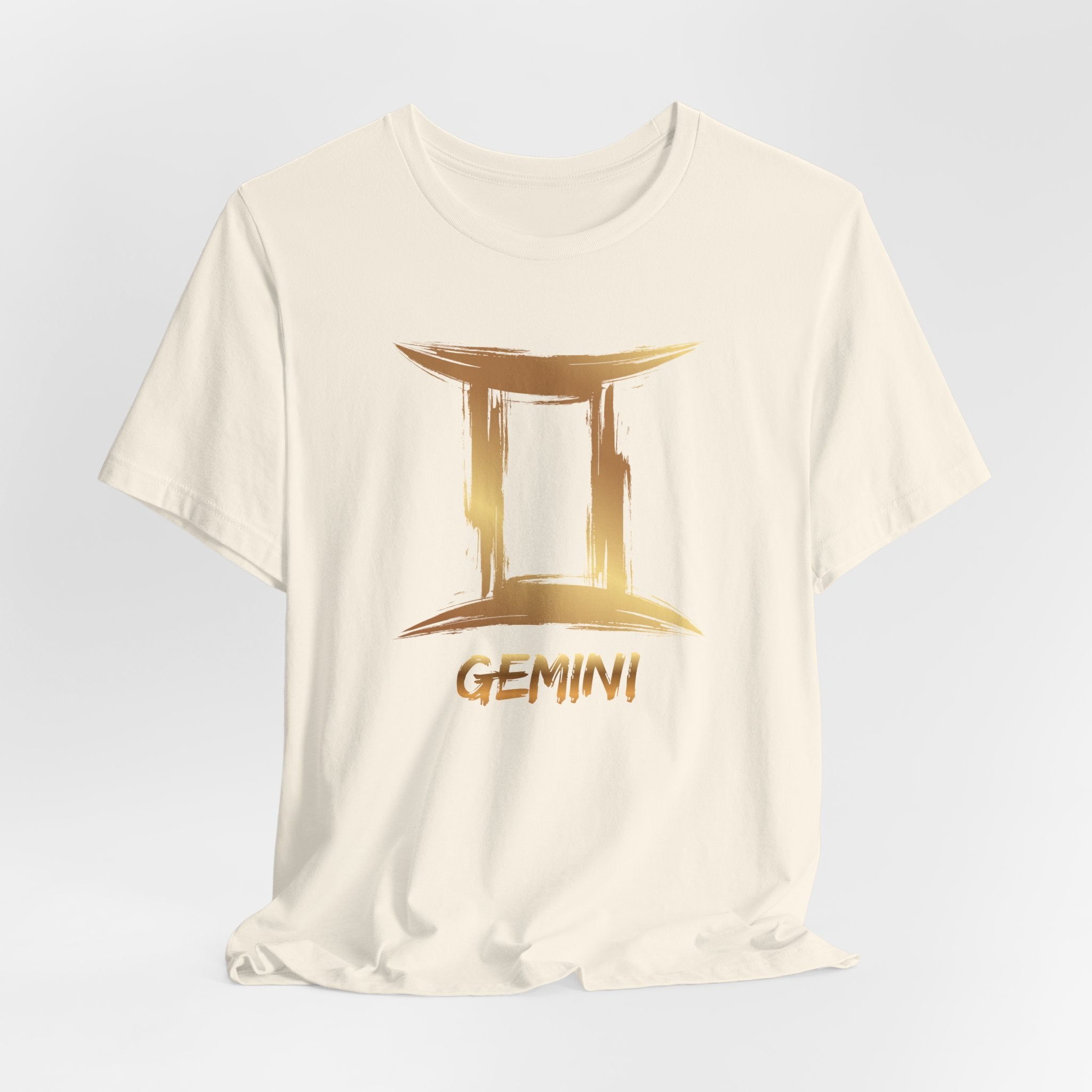 White t-shirt with gold Gemini zodiac sign design on a light gray background