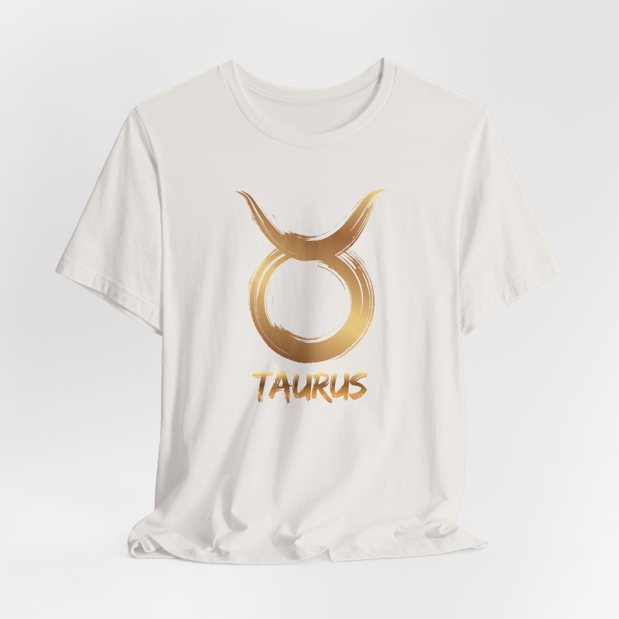 White t-shirt with gold Taurus zodiac symbol on a light gray background
