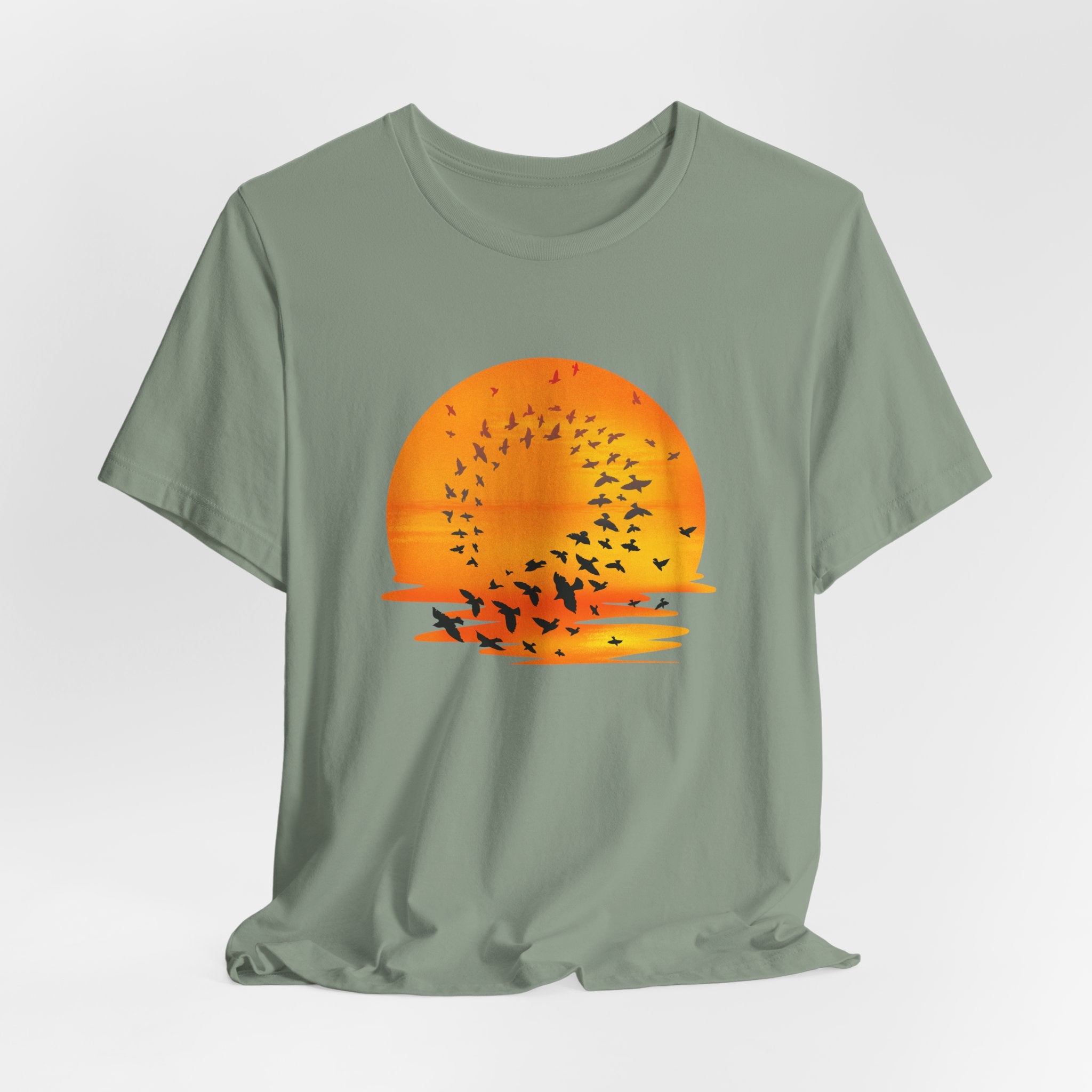 Green t-shirt with a sunset and bird design on a light gray background