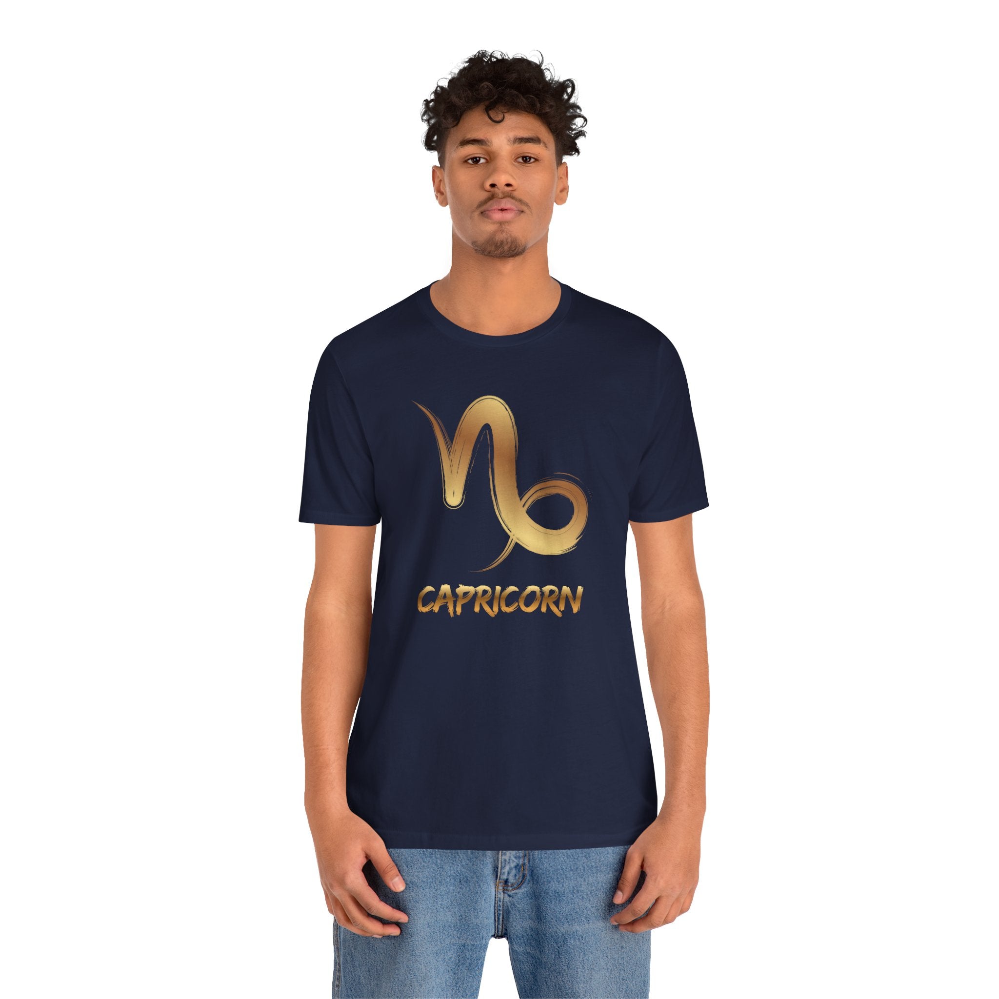 Person wearing a navy blue t-shirt with a gold Capricorn zodiac symbol on a white background