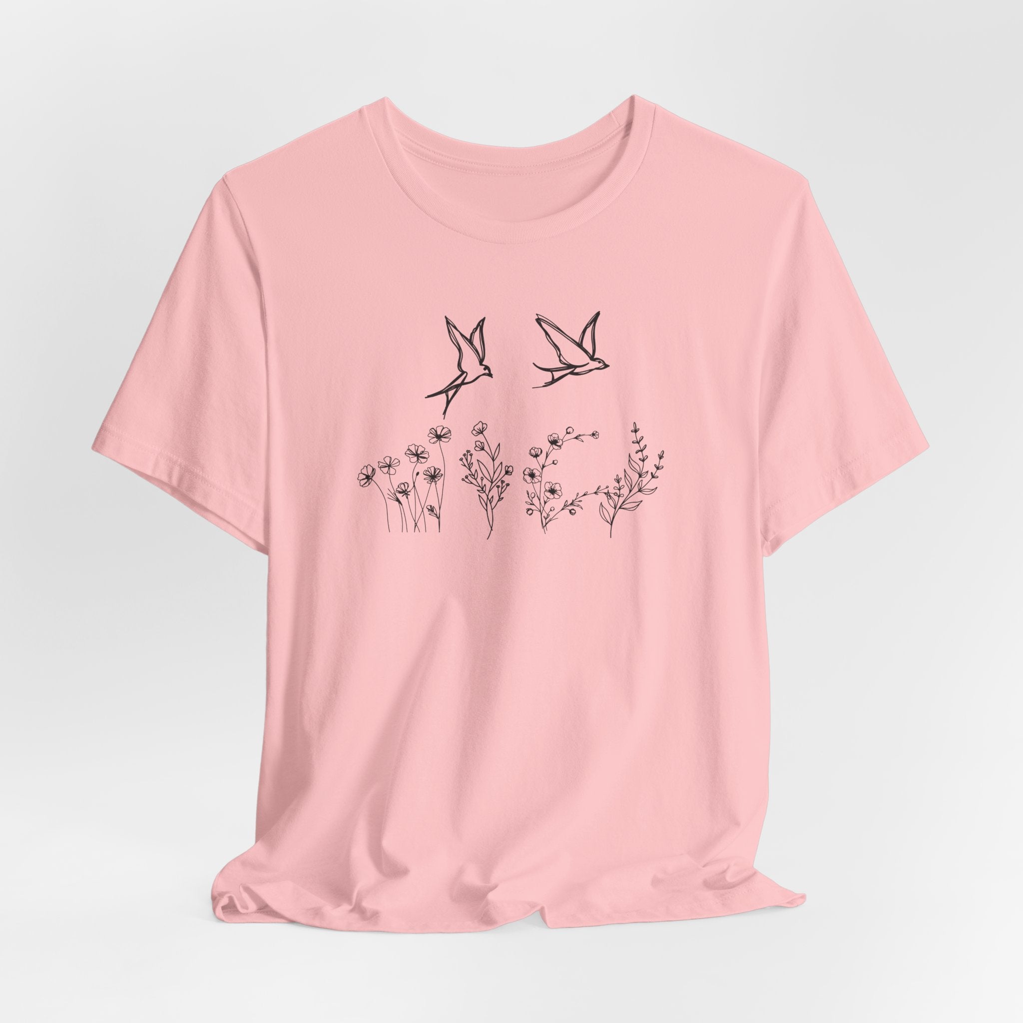 Pink t-shirt with black bird and floral design on a light gray background