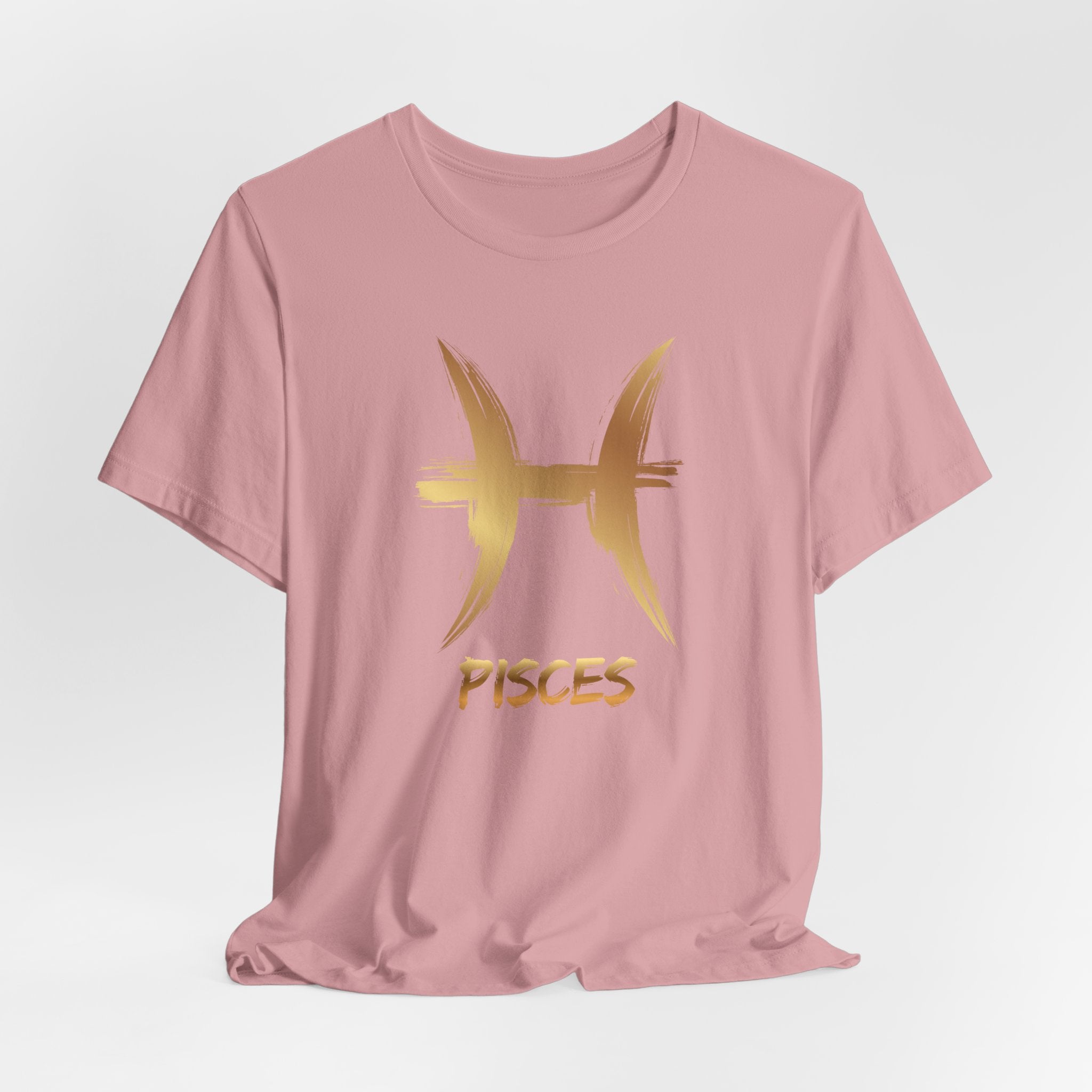 Pink t-shirt with gold Pisces symbol and text on a light gray background