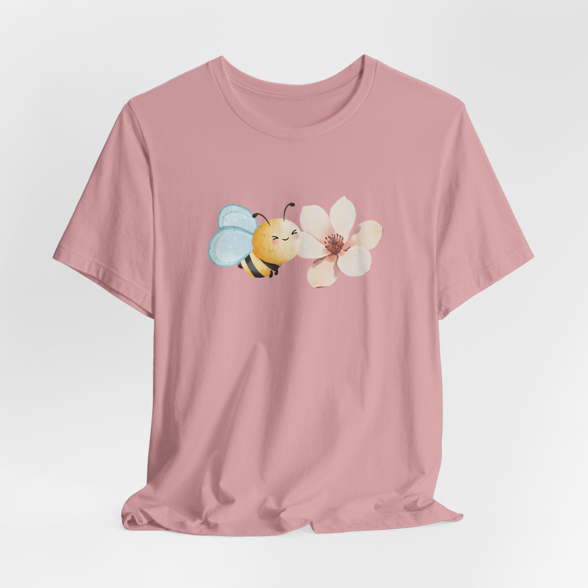 Pink t-shirt with a bee and flower design on a light gray background
