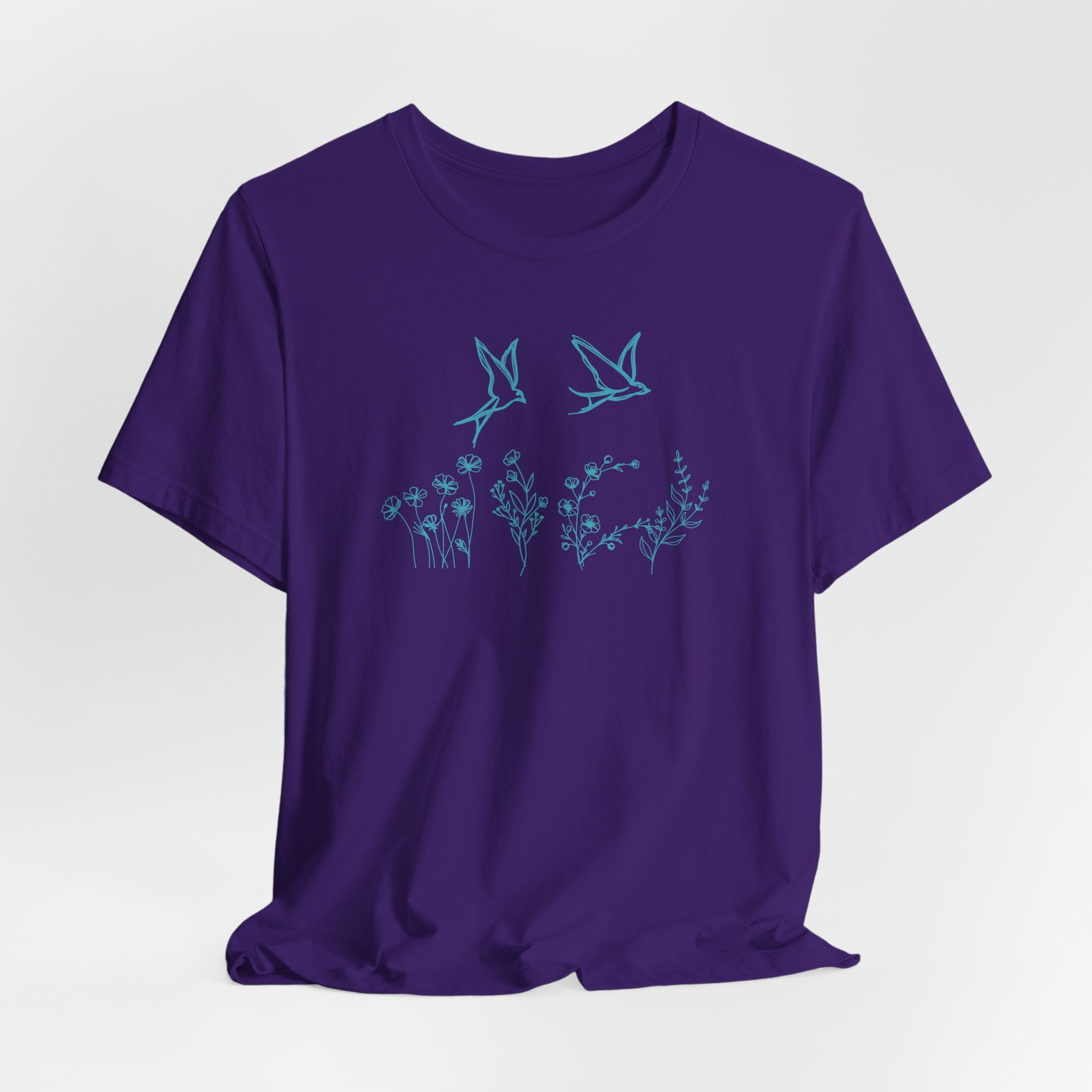 Purple t-shirt with blue floral and bird design on a white background