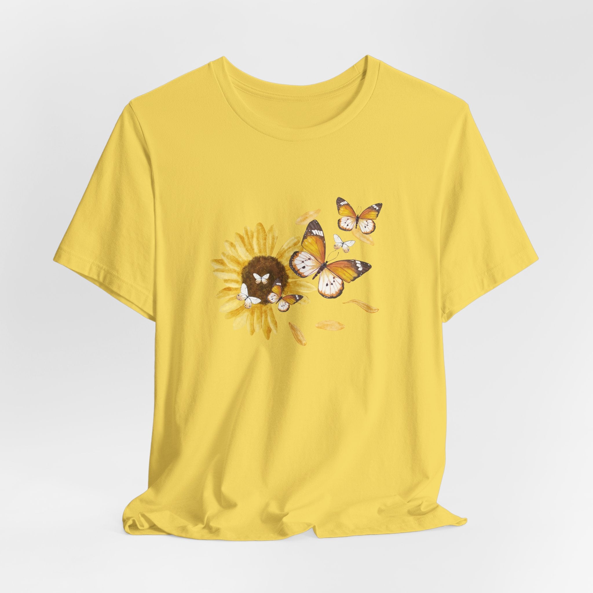 Yellow t-shirt with a sunflower and butterfly design on a light gray background