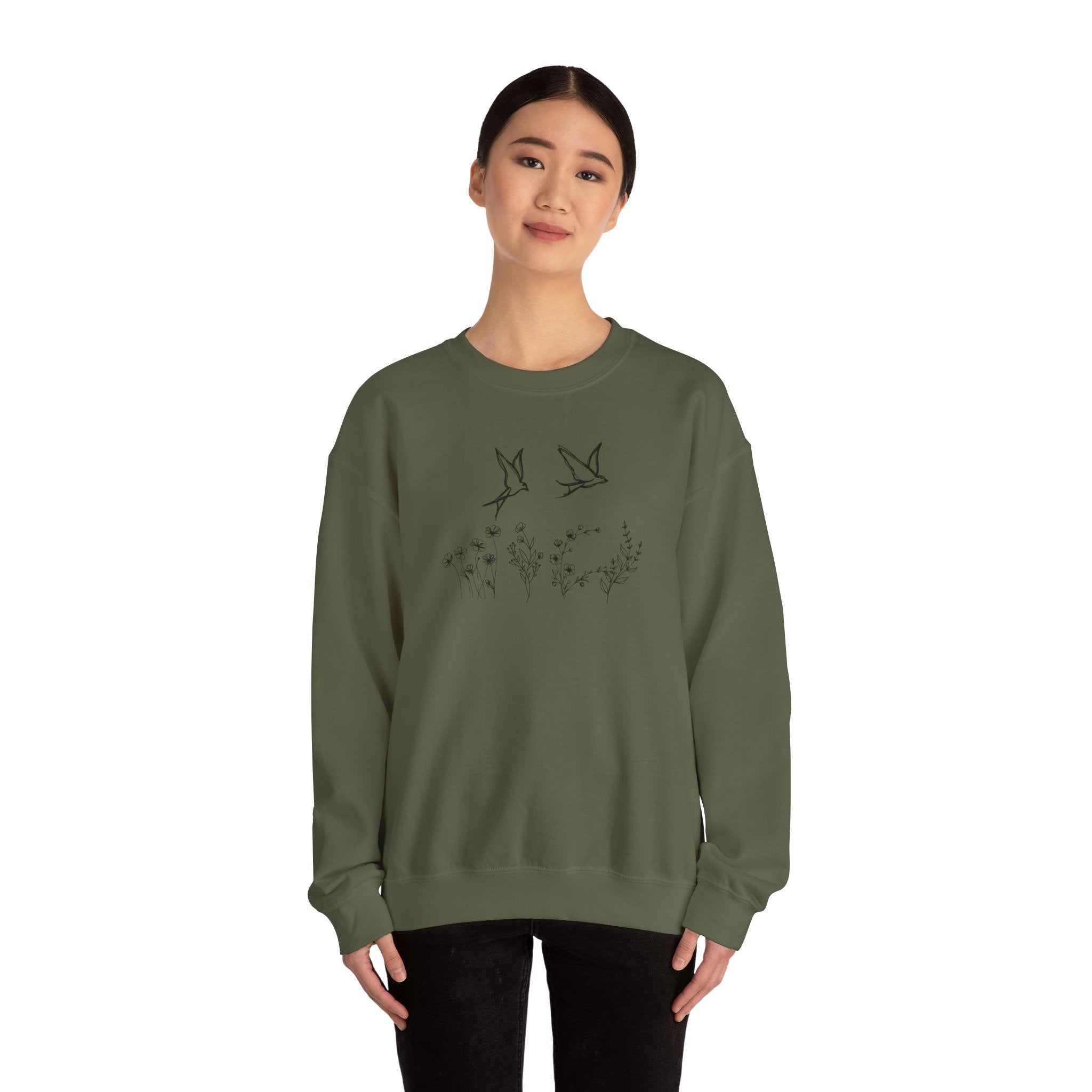 Person wearing a green sweatshirt with bird and flower graphics on a white background