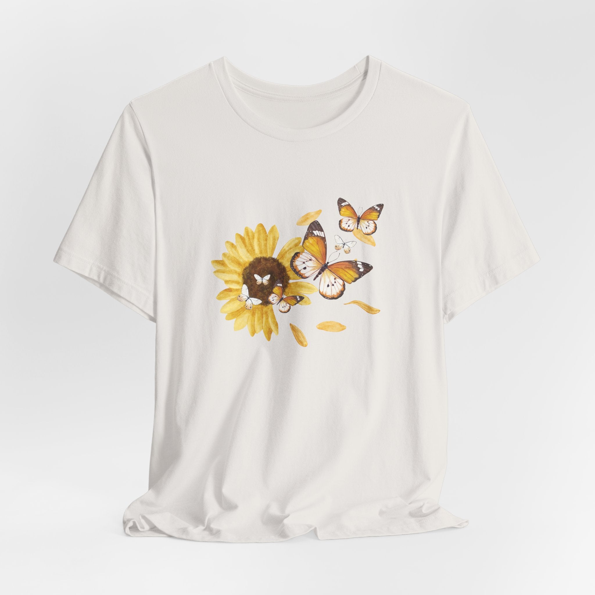 White t-shirt with a sunflower and butterfly graphic on a light gray background