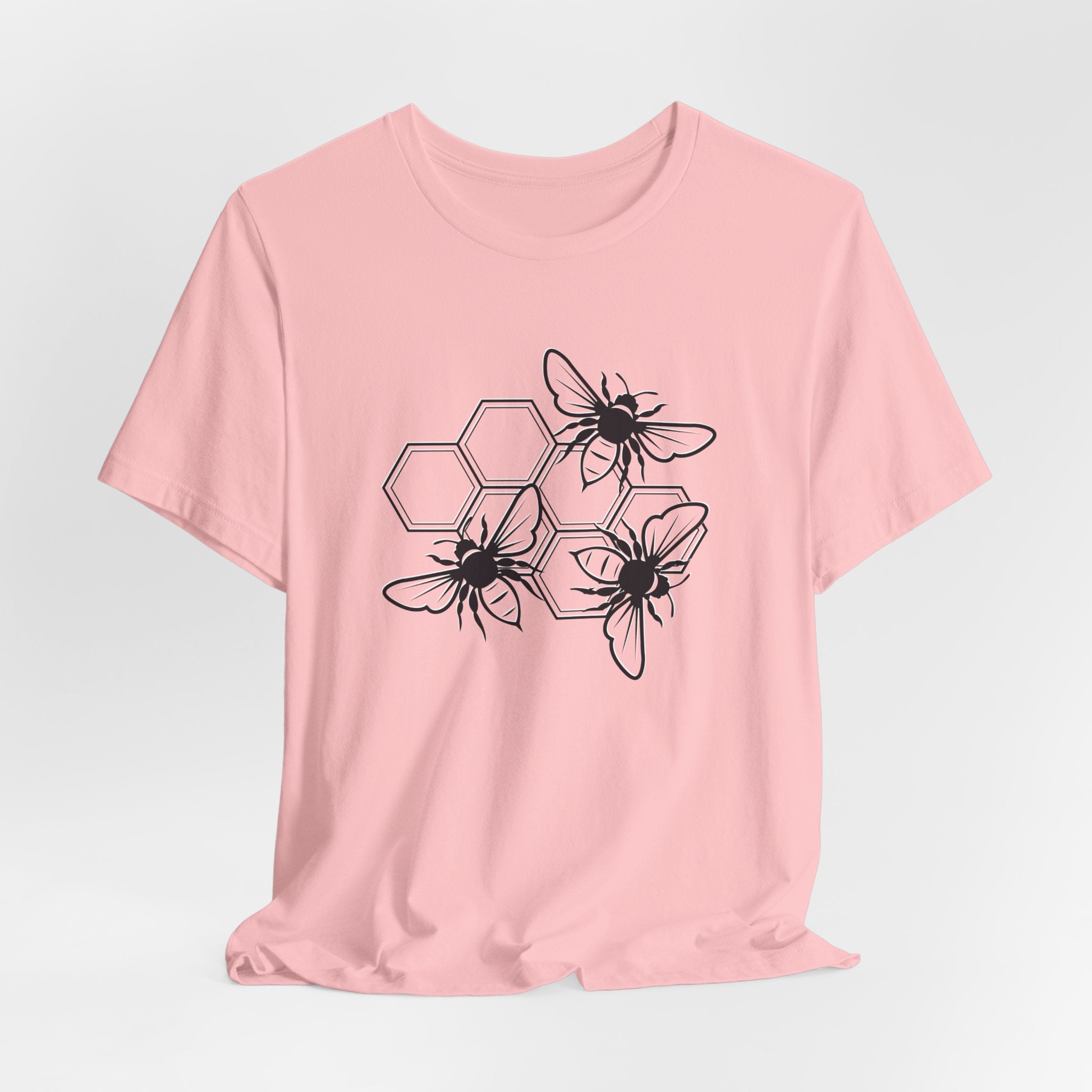 Pink t-shirt with black bee and hexagon design on a light gray background