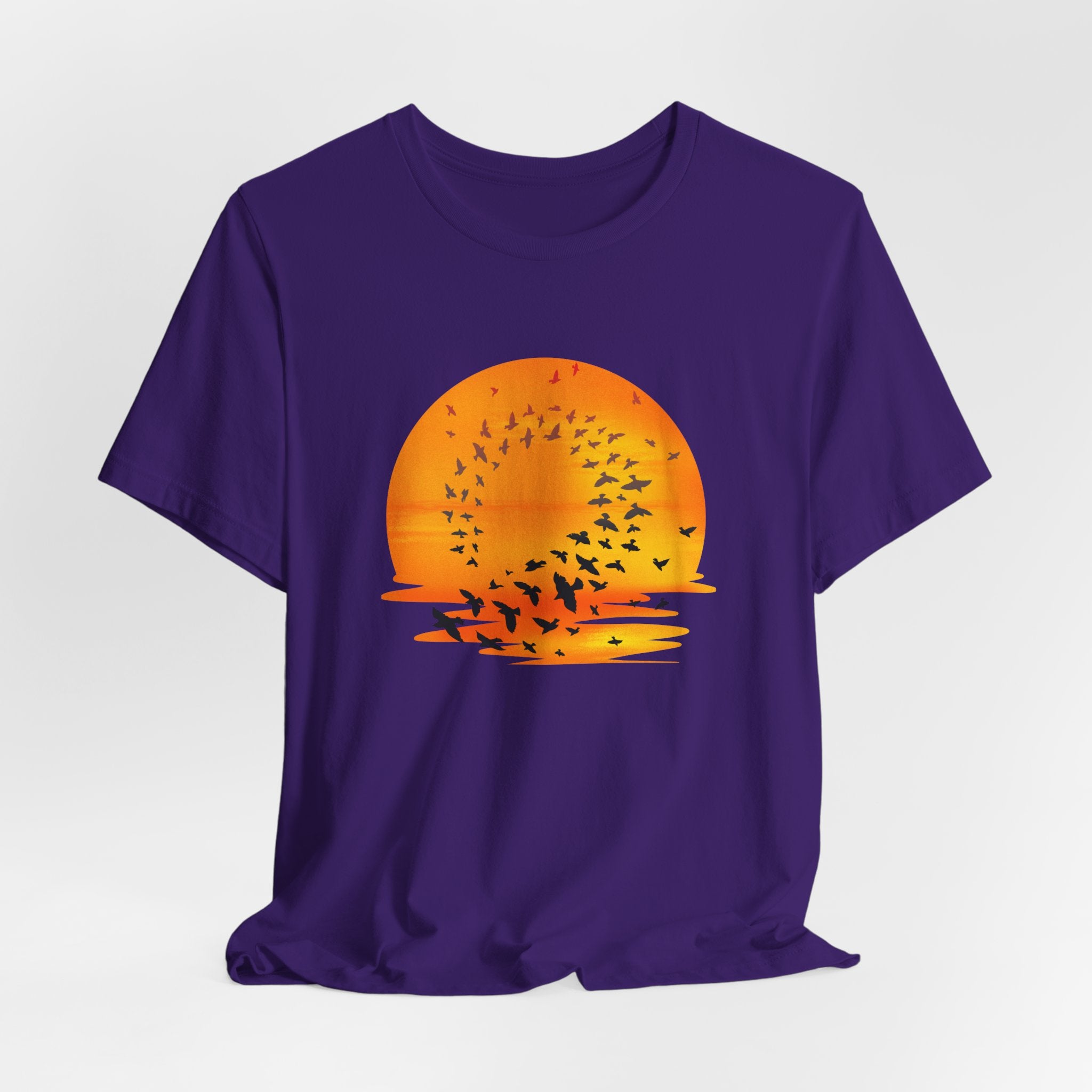 Purple t-shirt with an orange sunset and black birds design on a white background