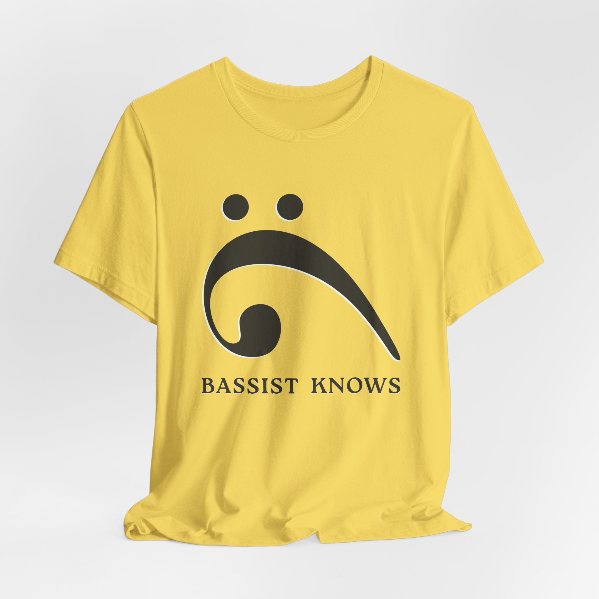 Yellow t-shirt with black bass clef and 'Bassist Knows' text on a light gray background