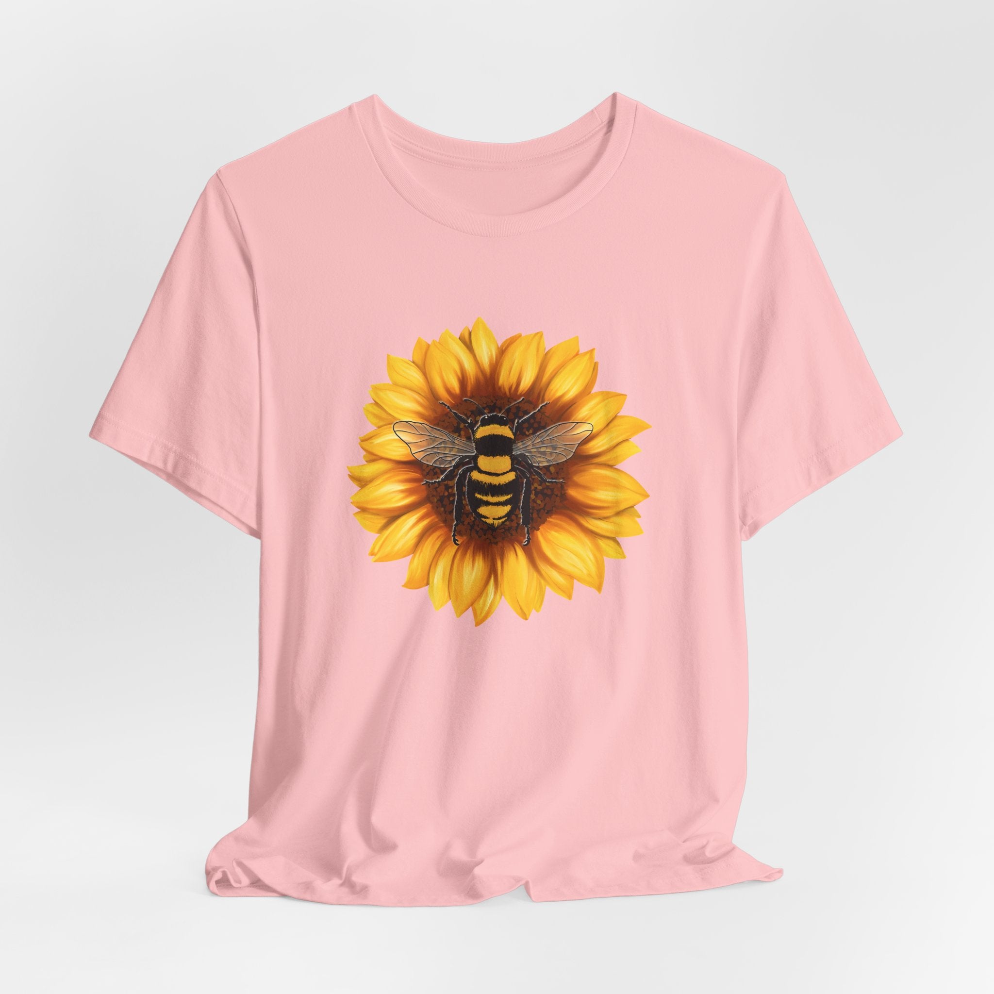 Pink t-shirt with a sunflower and bee design on a light gray background