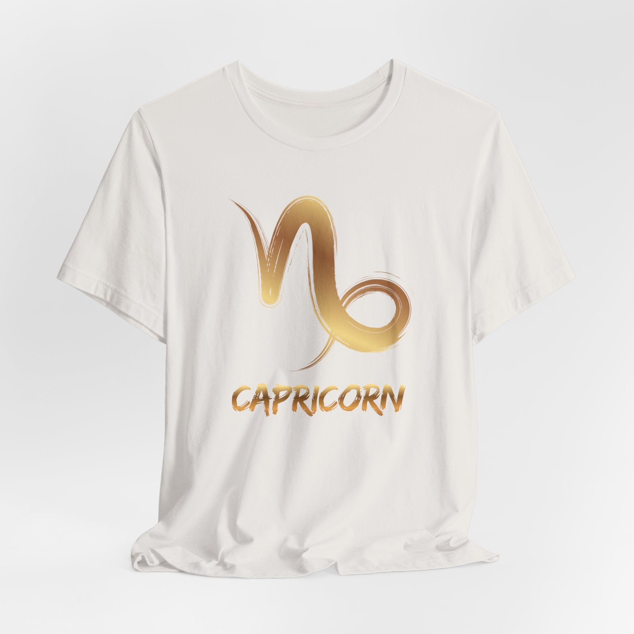 White t-shirt with gold Capricorn zodiac symbol on a light gray background