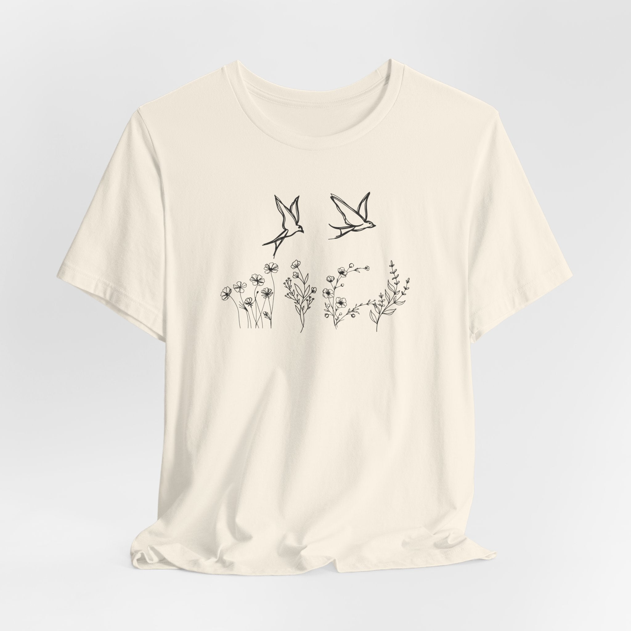 Beige t-shirt with black bird and flower design on a light gray background