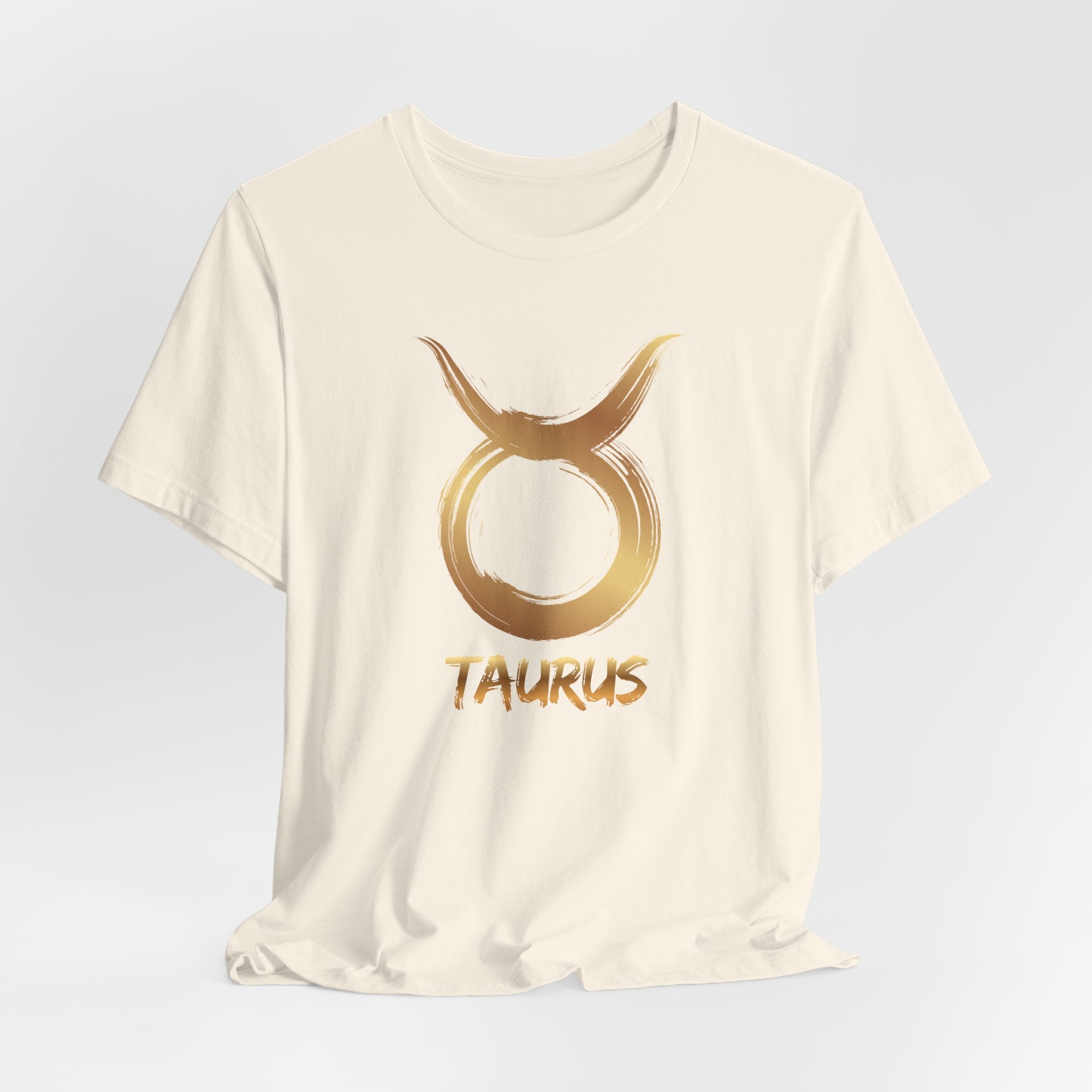 White t-shirt with gold Taurus zodiac symbol on a light gray background