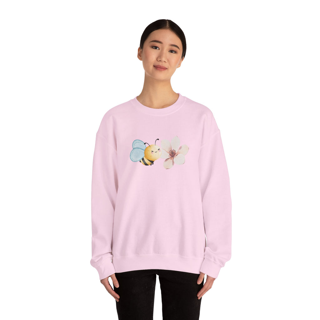 Person wearing a pink sweatshirt with bee and flower pattern on a white background