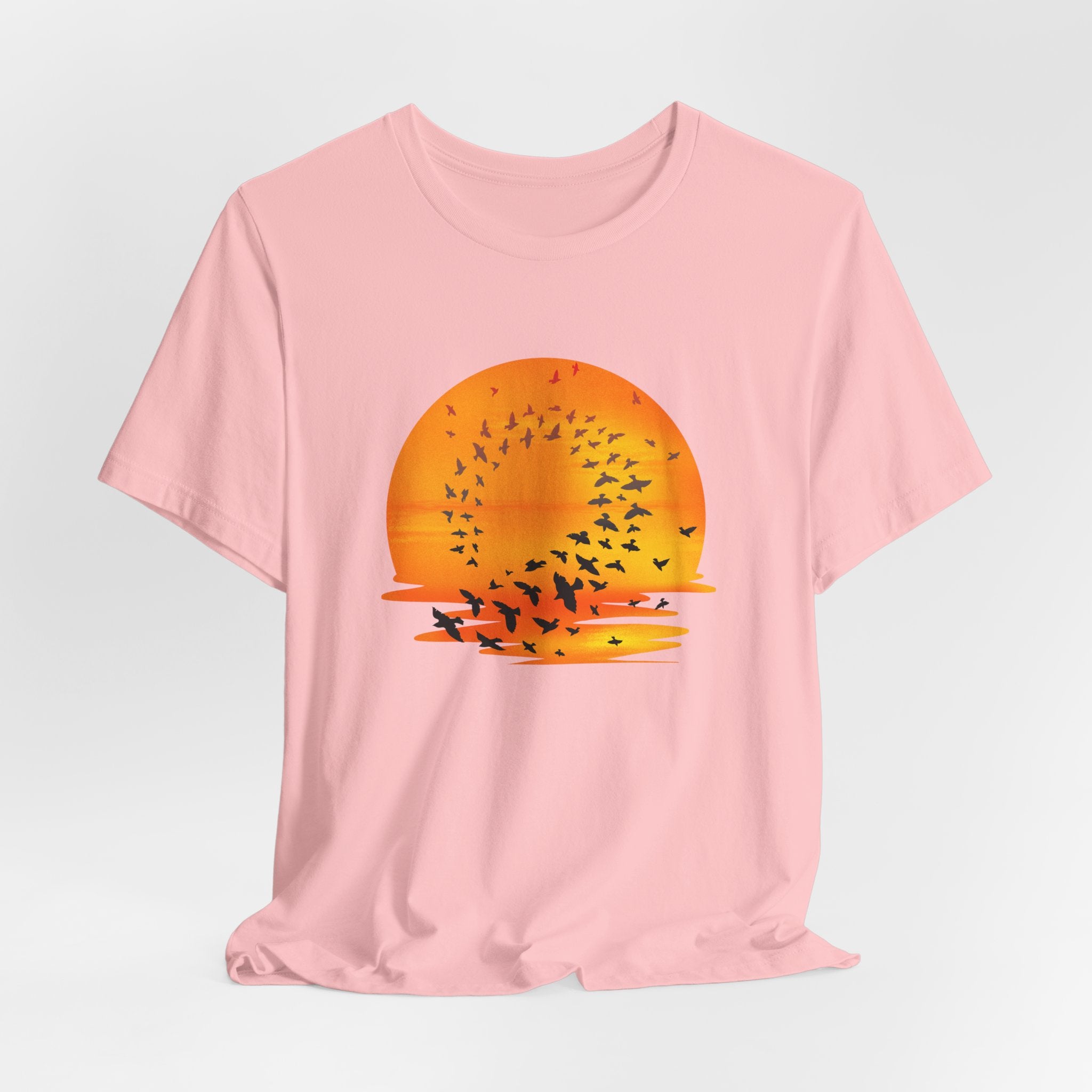 Pink t-shirt with a sunset and bird design on a light gray background
