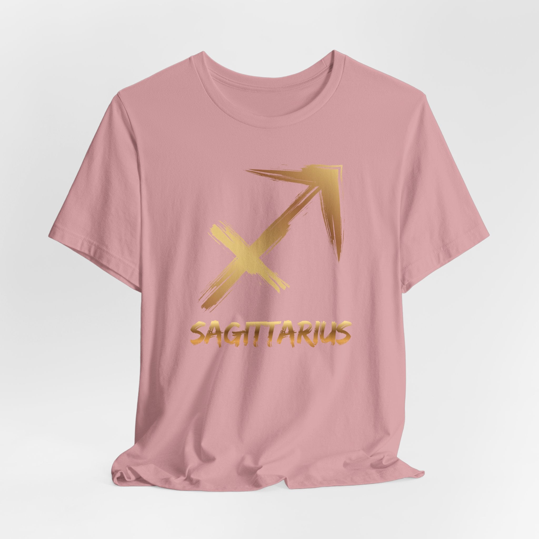 Pink t-shirt with gold Sagittarius symbol and text on a light gray background