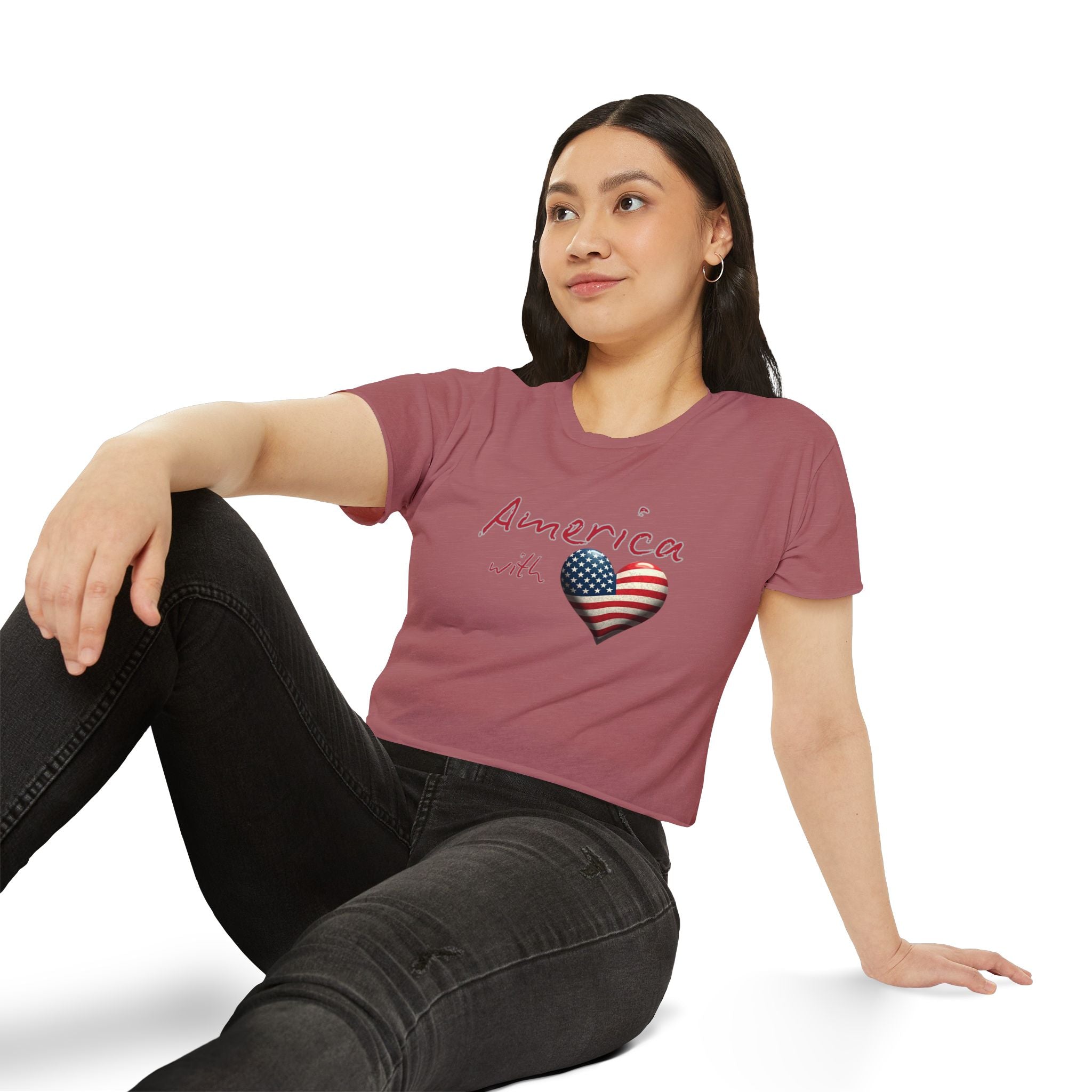 Woman wearing a pink t-shirt with 'America' and a heart design sitting on a white background