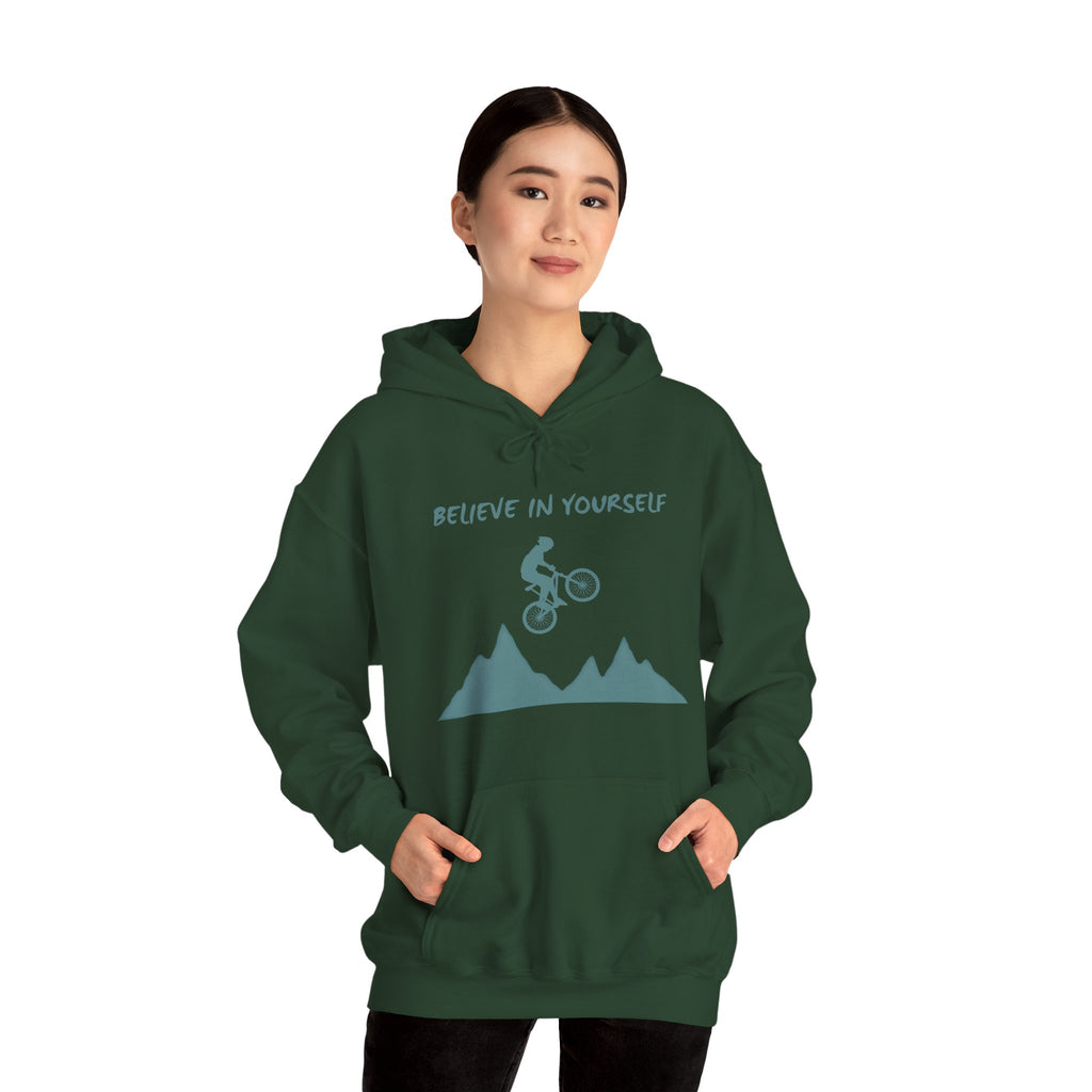Person wearing a green hoodie with a mountain and bicycle graphic and 'Believe in Yourself' text.