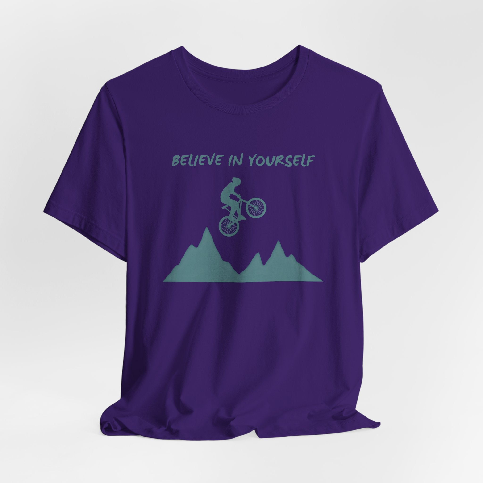 Purple t-shirt with mountain bike graphic and 'Believe in Yourself' text on a white background